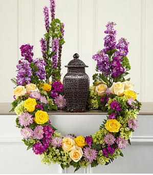 The FTD® Garden of Grace™ Arrangement - This masterpiece of floral sympathy creates a beautiful and reverential tabletop setting for an urn holding the cremated remains of your loved one. Handcrafted by a local FTD artisan florist, this stunning and original creation is perfect for formal visitation or memorial services. Constructed on a modified wreath frame, it combines cream and yellow roses, fuchsia Dianthus, purple Liatris and stock, lavender cushion pompons, green trachelium and hydrangea all accented with lush greenery including ivy vines.   Your purchase includes a complimentary personalized gift message.