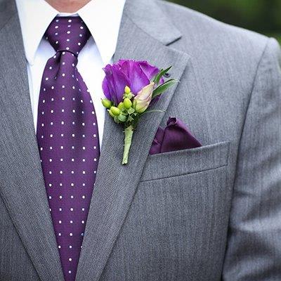 Purple boutonniere on a gray suit jacket with a matching pocket square