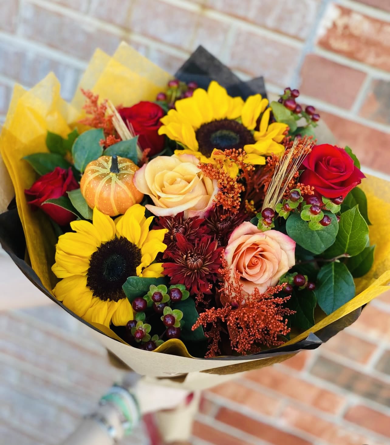 Bouquet of sunflowers and roses wrapped in yellow and black paper