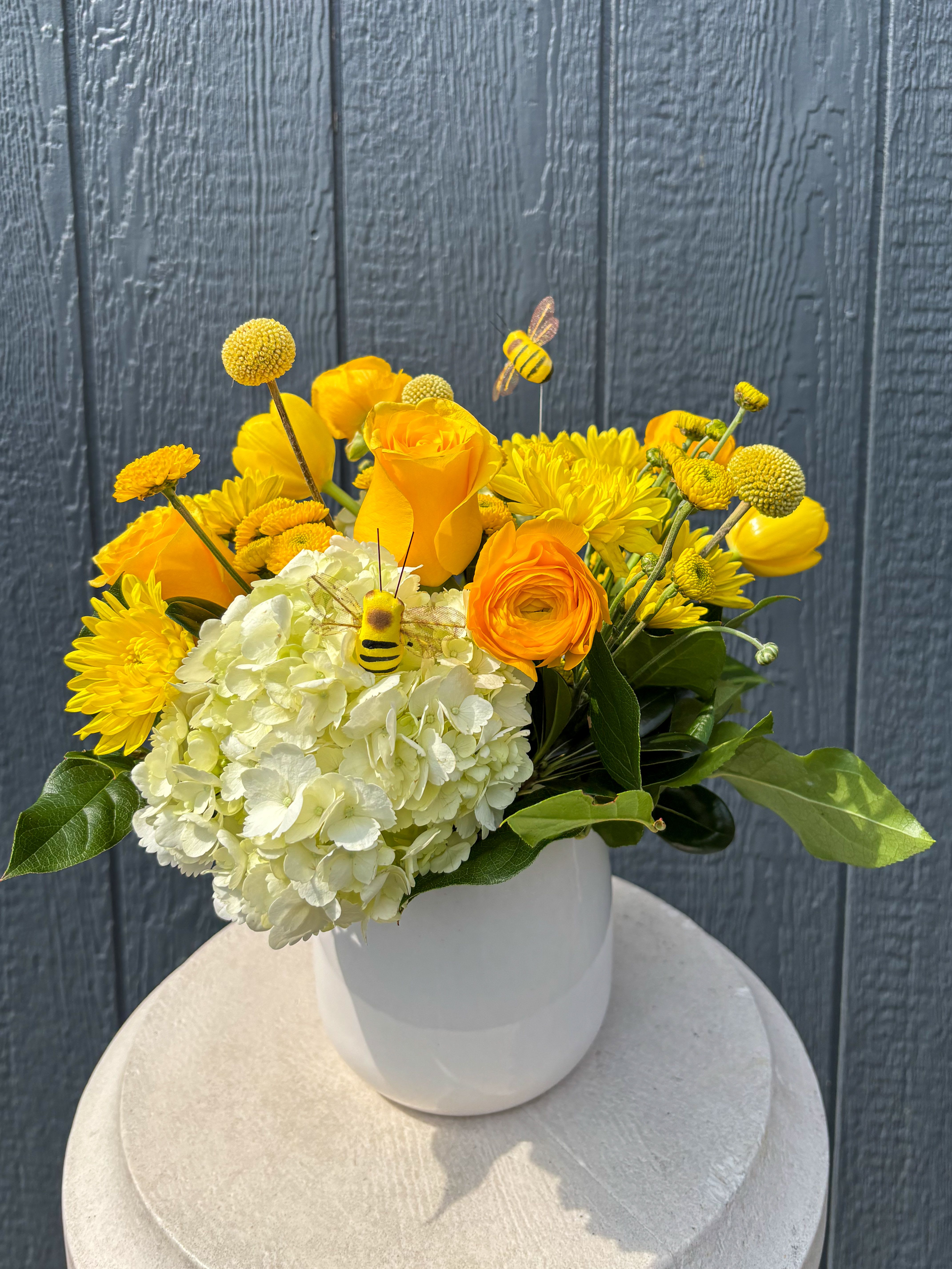 Bee Positive - Bring joy and brighten a loved ones day with our new arrangement called "Bee Positive". This arrangement is definitely causing a buzz with bright and cute button mums and yellow spray roses. We have included stunning white hydrangeas as well! 