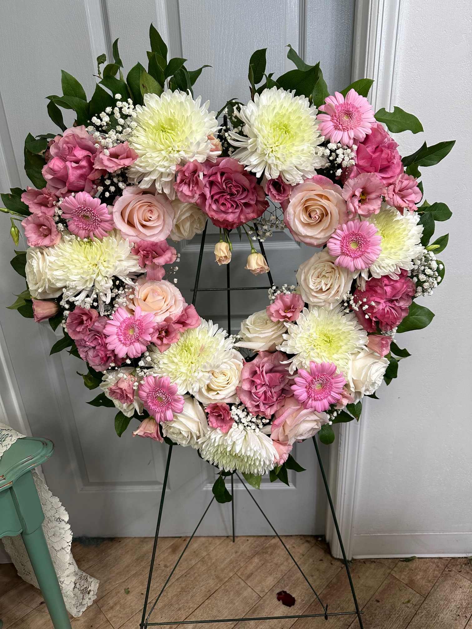 Heart-shaped floral wreath with pink and white flowers on a stand