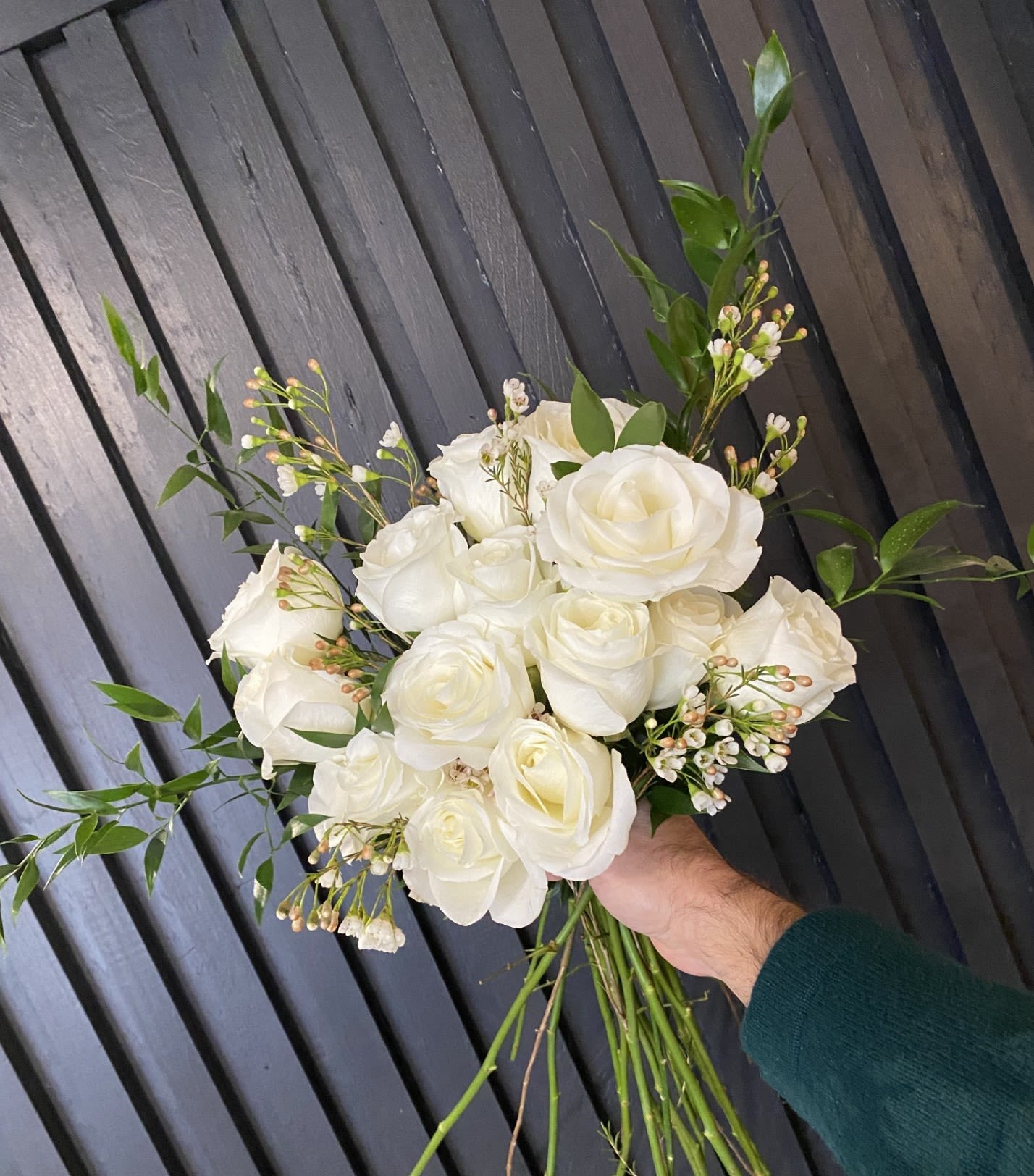Handtied Dozen White Roses - A bouquet of 12 long stemmed roses, in classic white, with sprigs of assorted greenery and Eucalyptus and a touch of Wax Flower filler. + $10 to arrange in glass vase