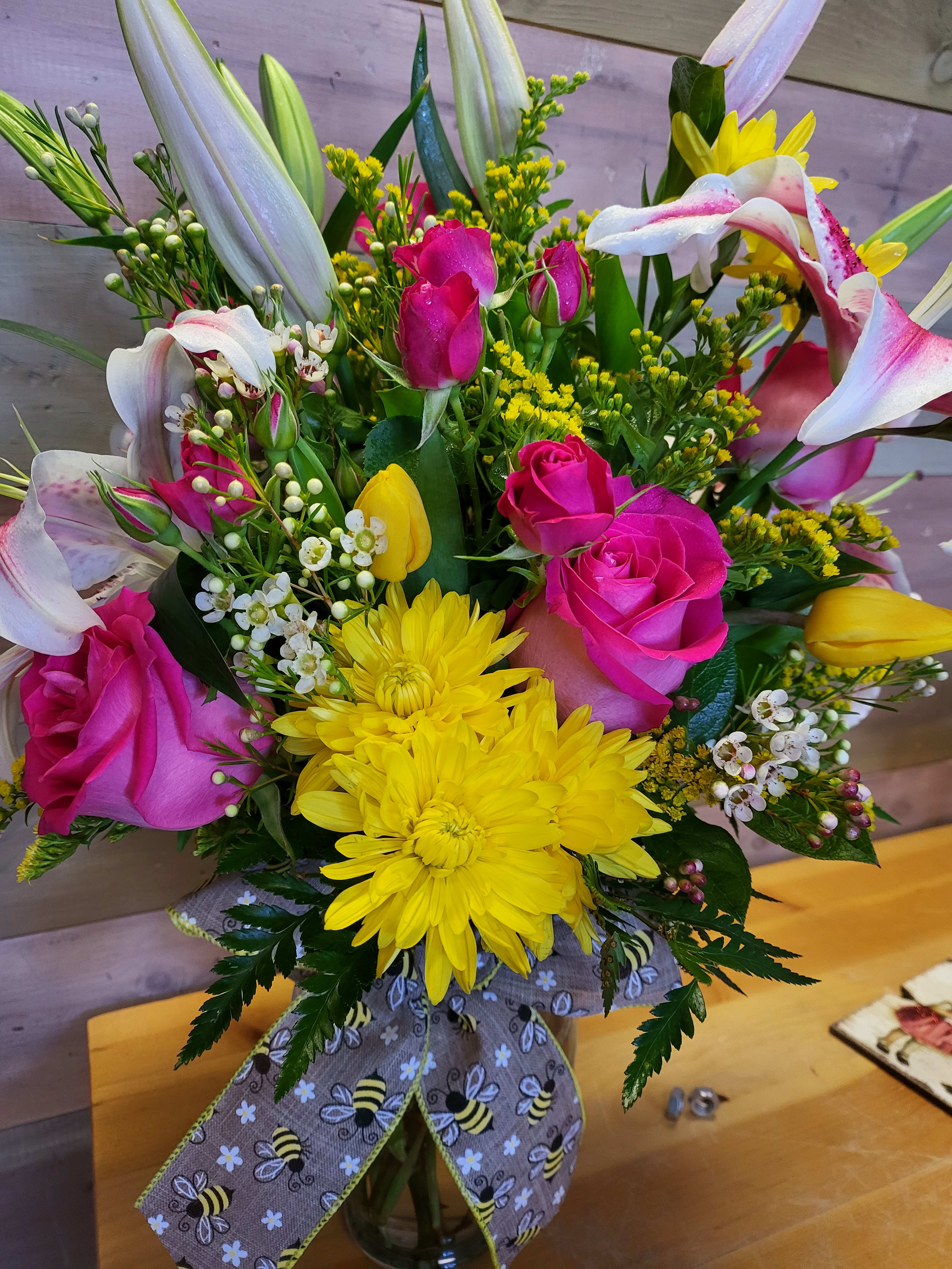 Bouquet of pink roses, yellow chrysanthemums, and white lilies in a vase
