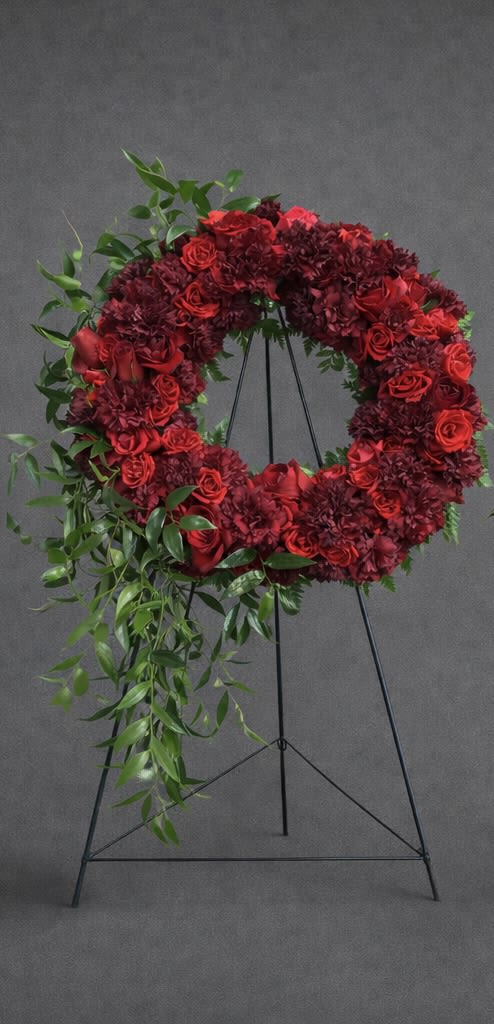 Crimson Red Sympathy Wreath - Our Red Sympathy Wreath is a special way to remember and honor a dearly departed. Vibrant red flowers are gathered to form the wreath to create a beautiful and loving presentation.