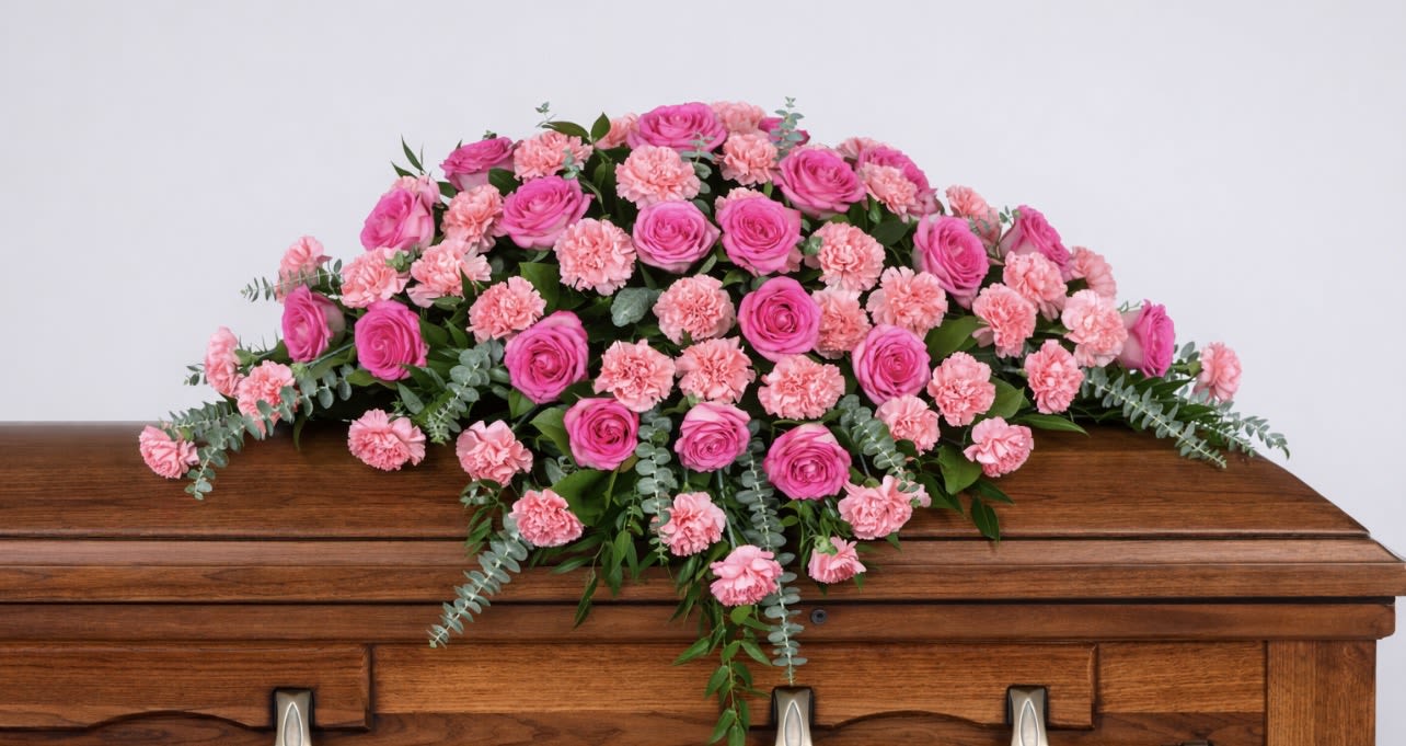 Pink rose and carnation spray on a wooden casket