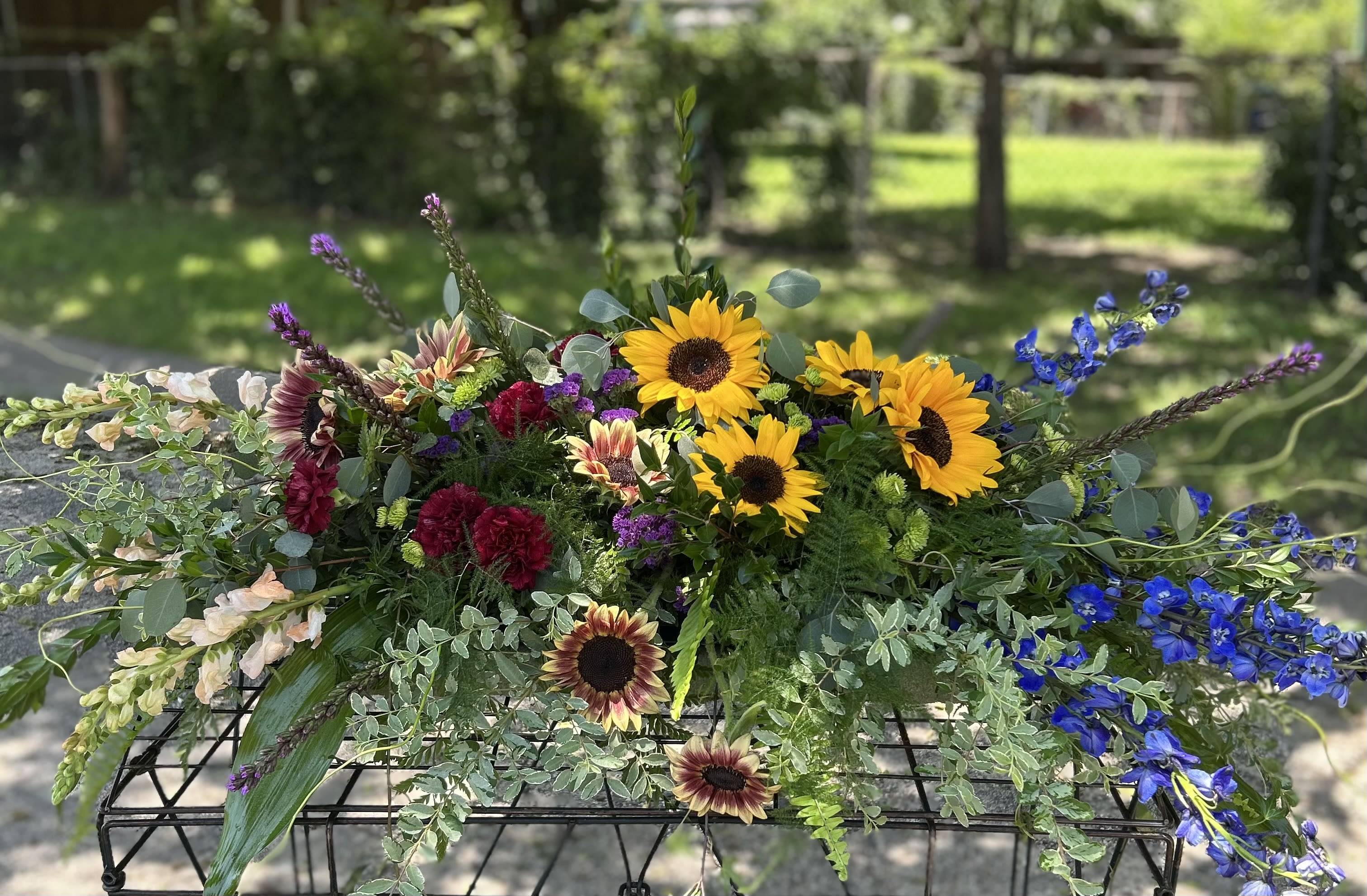 Mixed bouquet with sunflowers, blue delphinium, and burgundy blooms