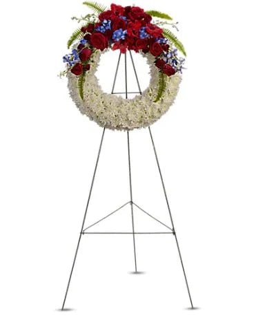 The Wreath of Glory - A stunning display of patriotism, strength and sympathy. This red, white and blue wreath delivers a lovely message about the dignity of the deceased. A lovely array of flowers such as blue hydrangea, red roses and spray roses, delicate blue delphinium, white cushion spray chrysanthemums and more create a circle of serene beauty.  Standard  DGT2411A