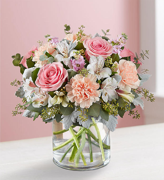 Blushing Blooms™ Bouquet - You’ll have them at first blush when they see this stunning bouquet. We’ve gathered a lush mix of blooms in soft shades of pink, peach and white for everyday elegance. Artistically designed in a stylish clear glass cylinder vase, it’s a heartfelt gift for birthdays, anniversaries or just to tickle someone pink. Blushing Blooms™ Bouquet is an all-around arrangement of pink roses and stock, peach carnations and white Peruvian lilies (alstroemeria); accented with dusty miller, eucalyptus and fresh greenery