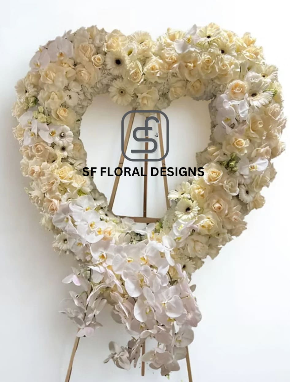 Large heart-shaped standing wreath of ivory roses, gerbera daisies, and orchids on a wooden easel
