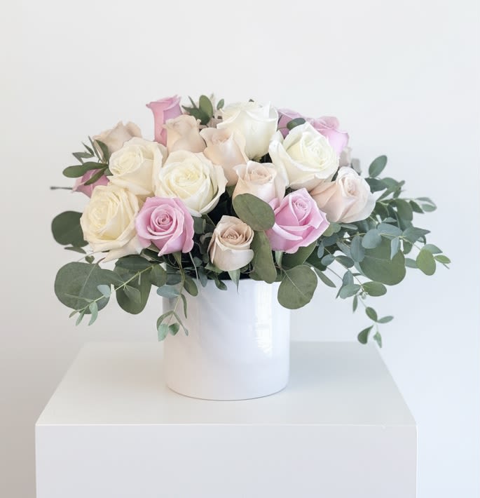 Pretty in pink - Cream, blush and soft pink roses accented with sage green eucalyptus in a white container 