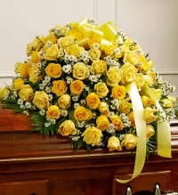 Yellow Rose Remembrance - A beautiful and radiant casket cover designed to express love, honor, and remembrance.  This elegant tribute features vibrant yellow roses arranged gracefully across the casket and accented with fresh greenery and delicate white monte casino asters, creating a soft contrast and natural garden feel. A yellow ribbon bow adds a warm finishing touch to this meaningful display. Yellow roses traditionally symbolize friendship, warmth, and cherished memories, making this arrangement a heartfelt farewell.  Available in 25, 50, or 75 roses, allowing you to choose the size that best honors your loved one. Each piece is thoughtfully handcrafted to create a timeless and uplifting tribute. 