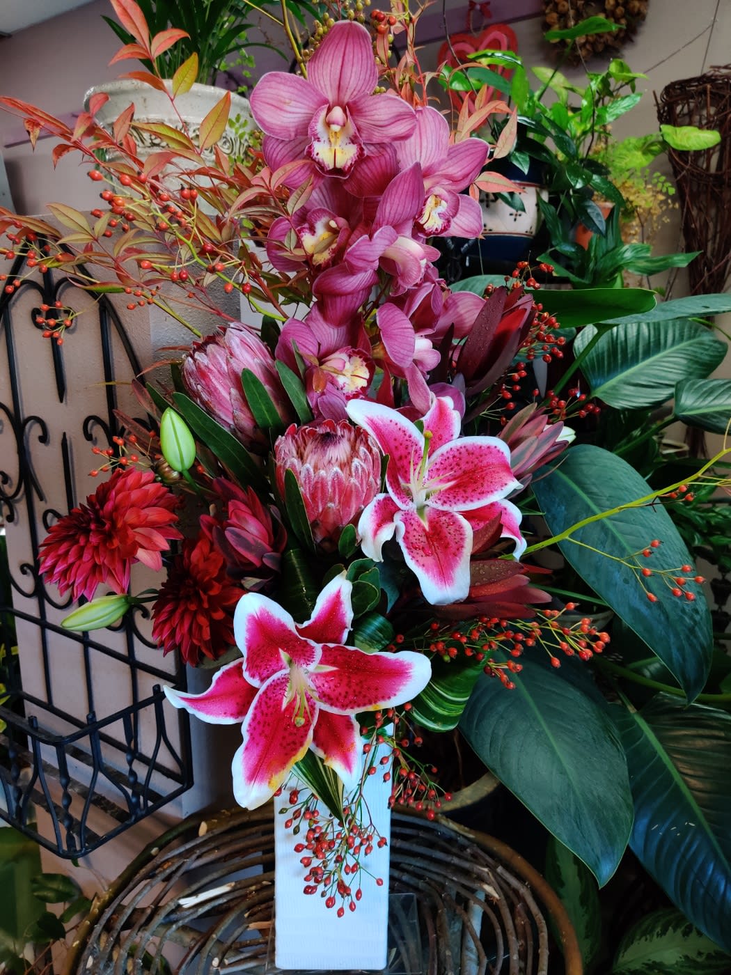 Pink Floral Fantasy - Contains Cymbidium Orchid, Stargazer lilies, Dahlia, Protea, Safari Sunset, Nandina, willow in a tall ceramic container 