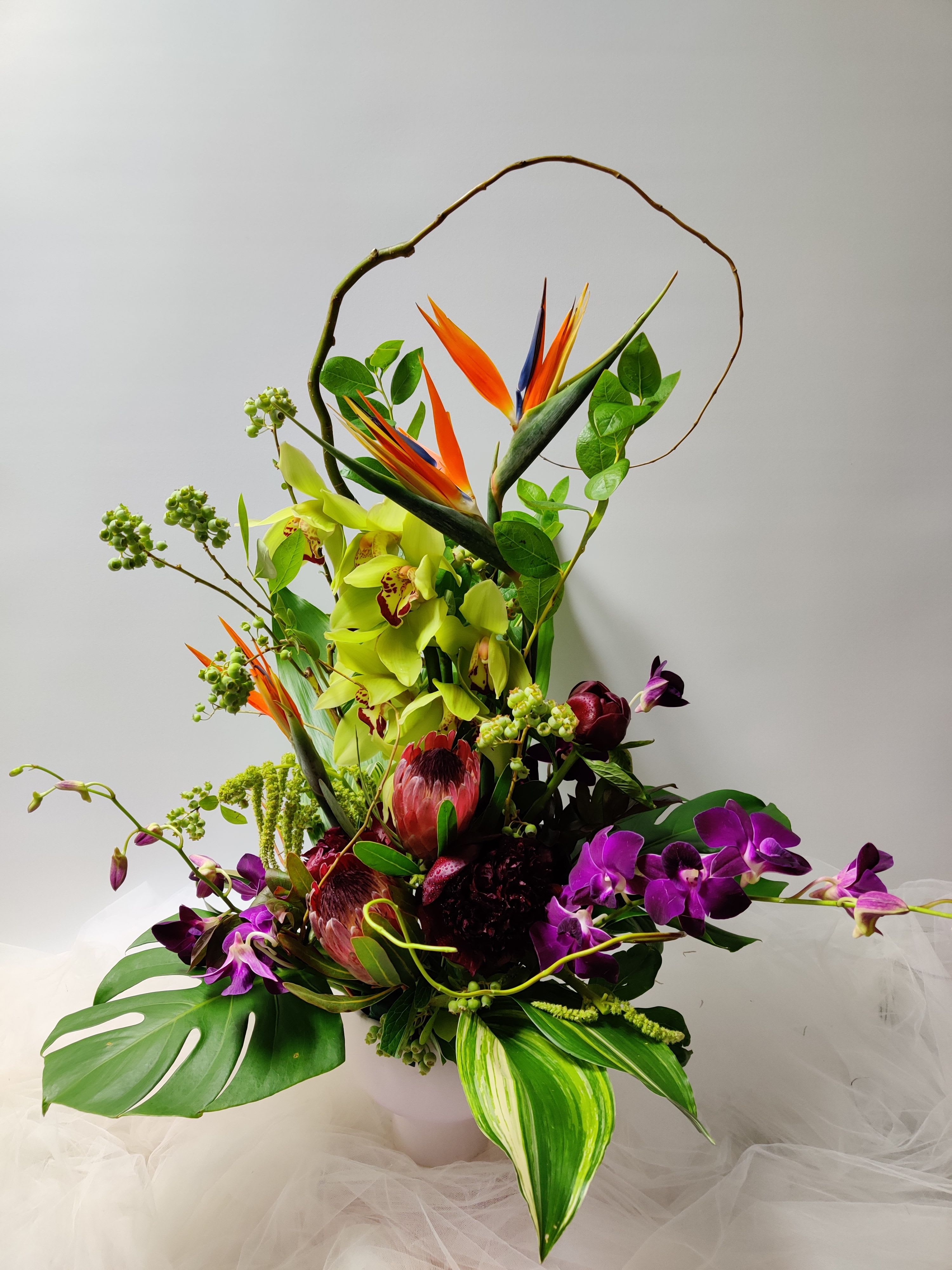 Velvet Zen - One of our beautiful Ikebana style arrangements made with cymbidium orchids, birds of paradise, protea, peonies, orchids, blueberries, and elegant assorted greens.