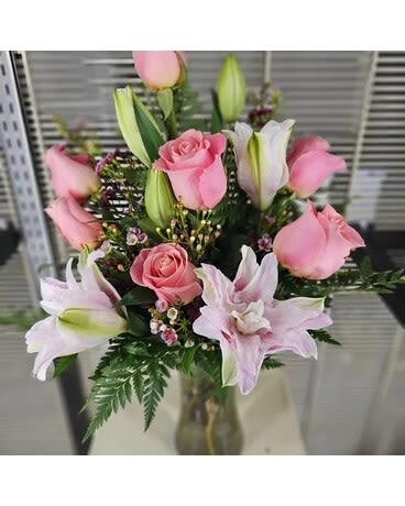Pink roses and lilies arranged in a glass vase