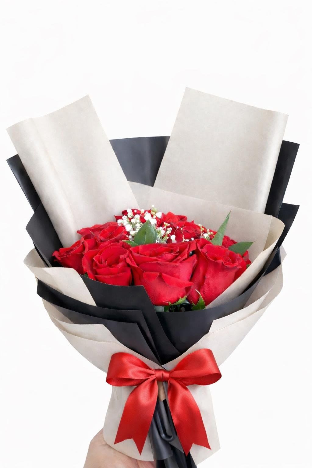 Velvet &amp; Noir  - A stunning hand-tied bouquet featuring twelve velvety red roses at the peak of their bloom. Nestled among delicate sprigs of white baby’s breath and fresh greenery, the arrangement is encased in a contemporary multi-layered wrap of matte black and kraft cream paper. Finished with a vibrant crimson satin bow, it’s the ultimate statement of love and luxury.