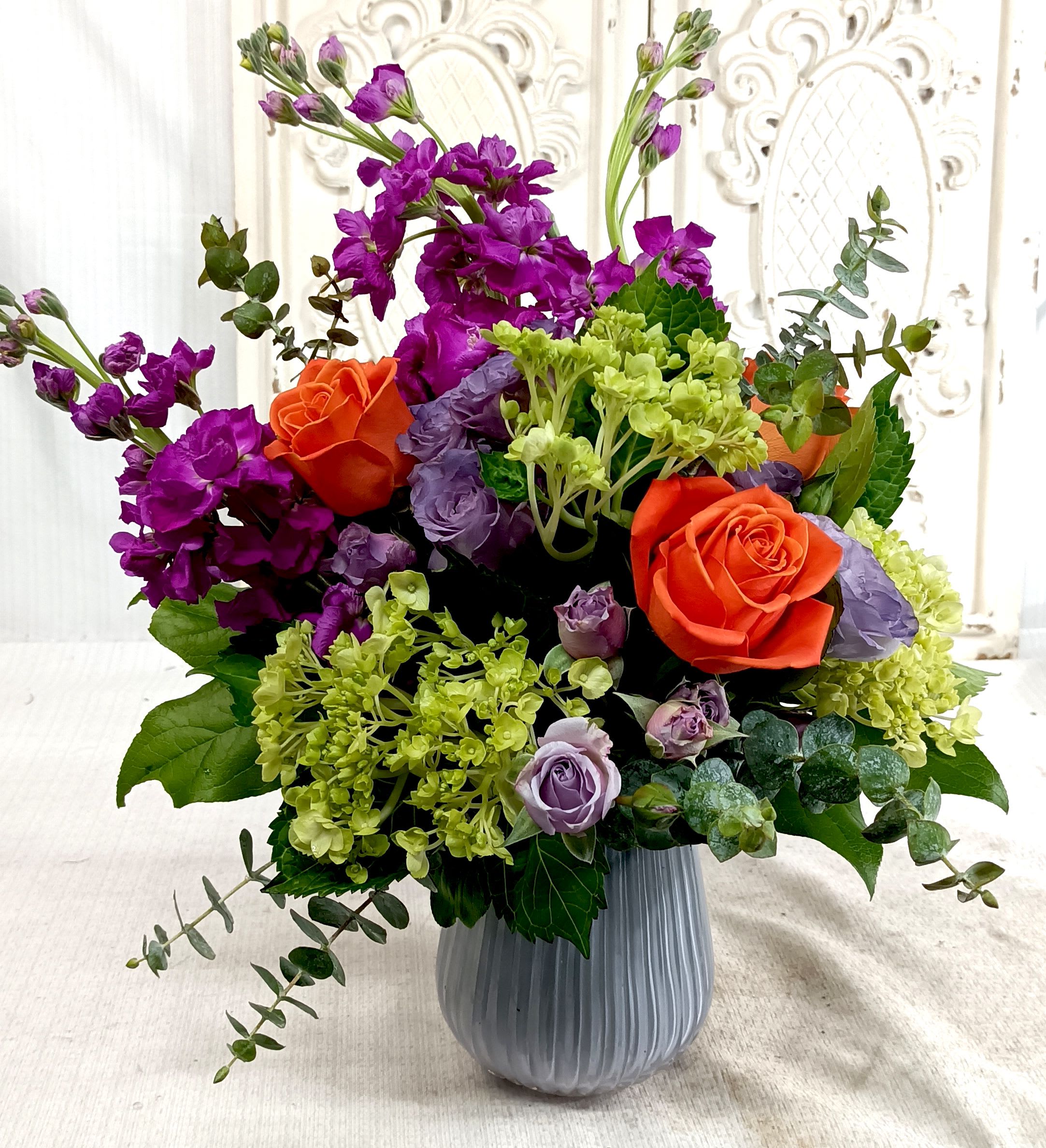 Summer Celebration - Assorted Brightly colored Blooms in a light Lavendar Vase