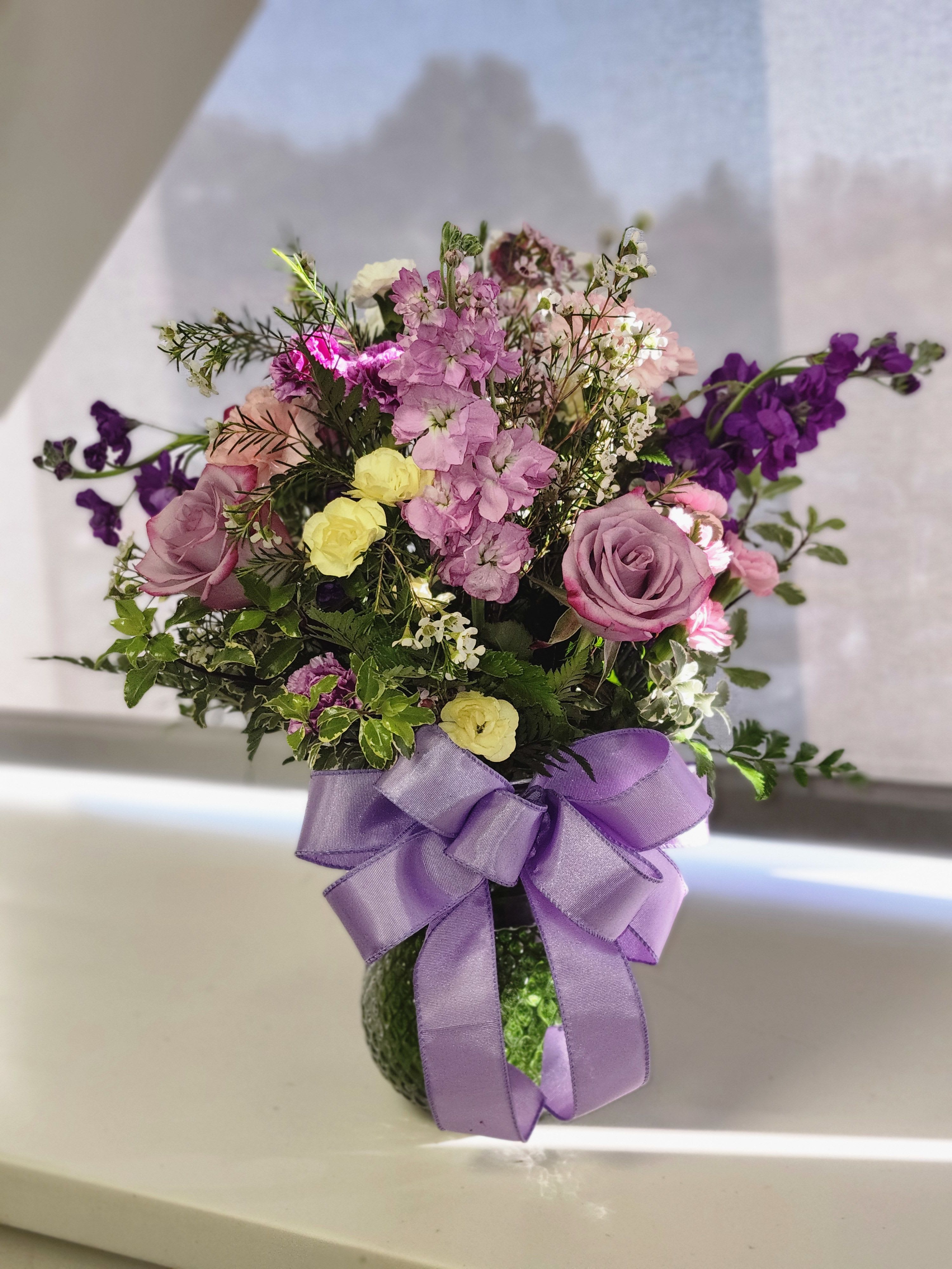 Purple Smile - Colors of purple, lavender, yellow and white. Combination of Roses, stock and mini carnations  great for get well, just because and Birthdays.
