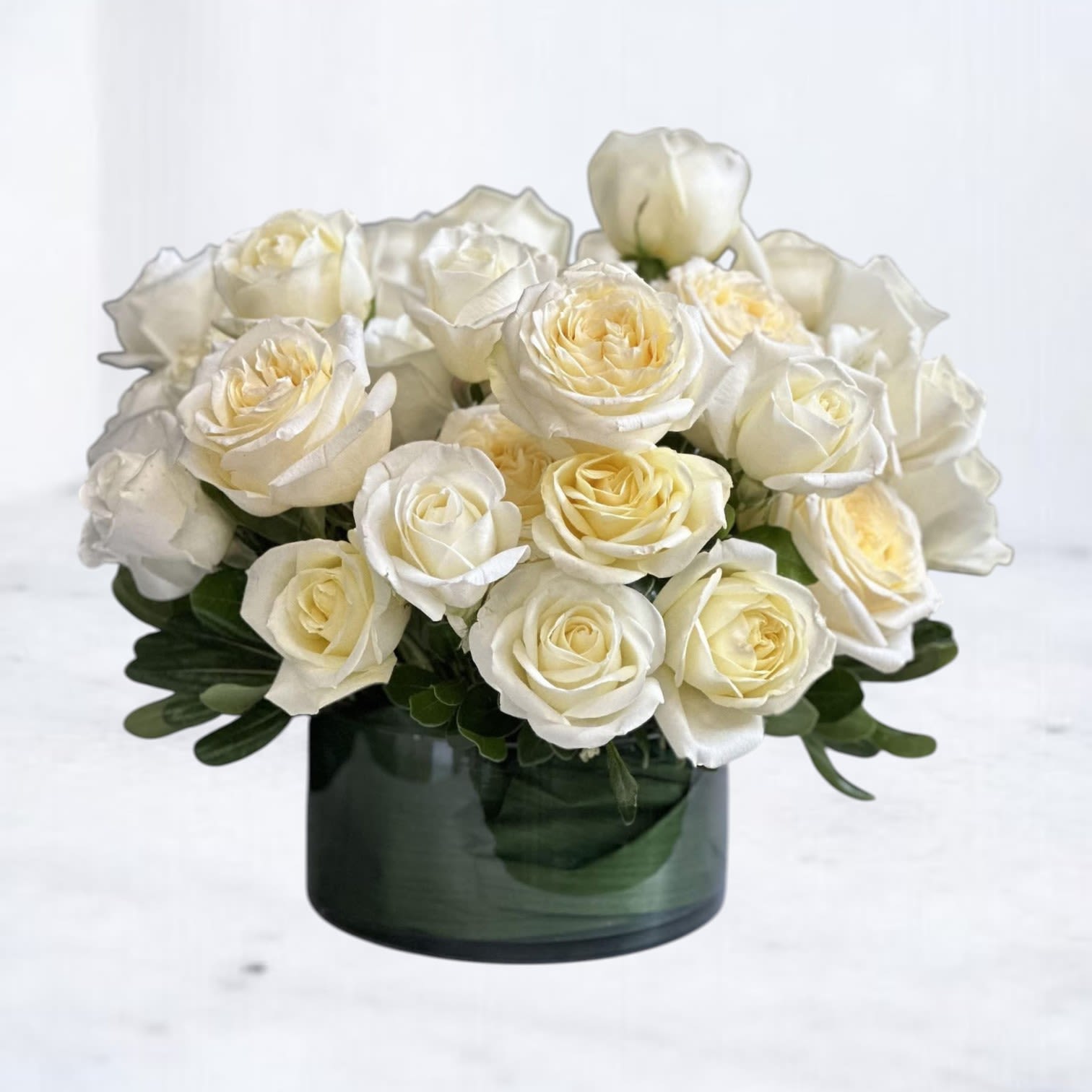 Three Dozen White Roses - The Three Dozen White Roses arrangement is a timeless expression of elegance and refinement. Featuring 36 premium white roses, this design is artfully arranged in a modern clear glass cube, allowing the natural beauty and fullness of each bloom to take center stage.  White roses symbolize grace, sincerity, and remembrance, making this arrangement an ideal choice for sympathy and memorials, weddings and anniversaries, corporate gifting, or elevated home décor. The clean, monochromatic palette feels serene and sophisticated, offering impact without excess.