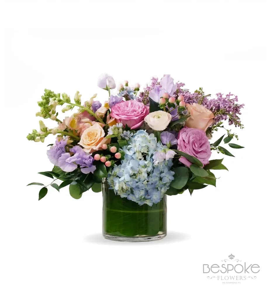 Secret Garden - This elegant arrangement features lush hydrangeas, garden roses, sweet peas, and vibrant hypericum berries in soft blush, lavender, and sky-blue tones. The delicate mix of textures creates a fresh, timeless garden-inspired design—perfect for Mother’s Day, welcoming a new baby, or brightening any space.