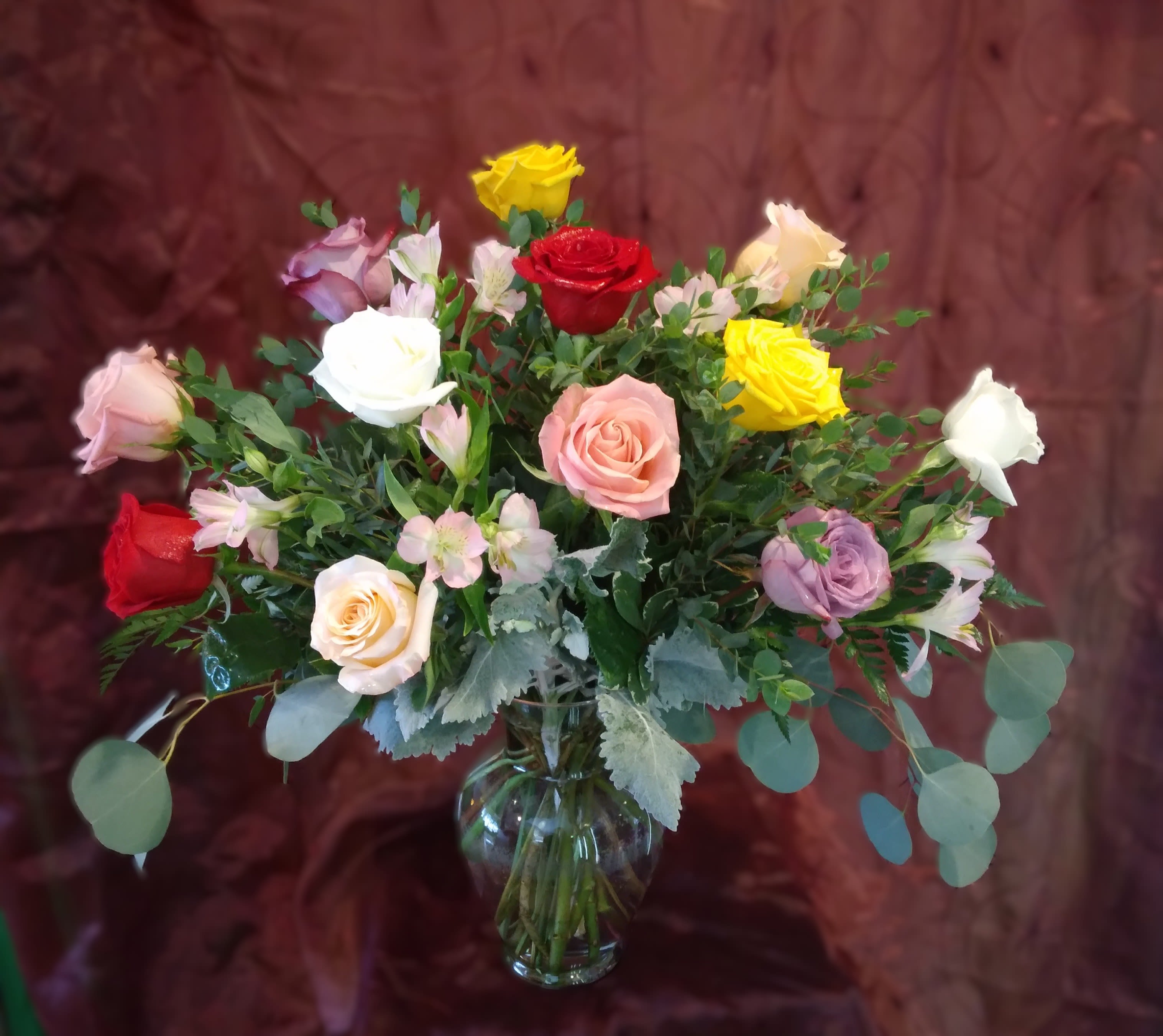Roses in Multi Colors ~ Flower A Day - Premium one dozen multi-colored roses arranged beautifully in a clear glass vase. Assorted foliage may vary.  Perfect for any occasion, or just a pick-me-up!