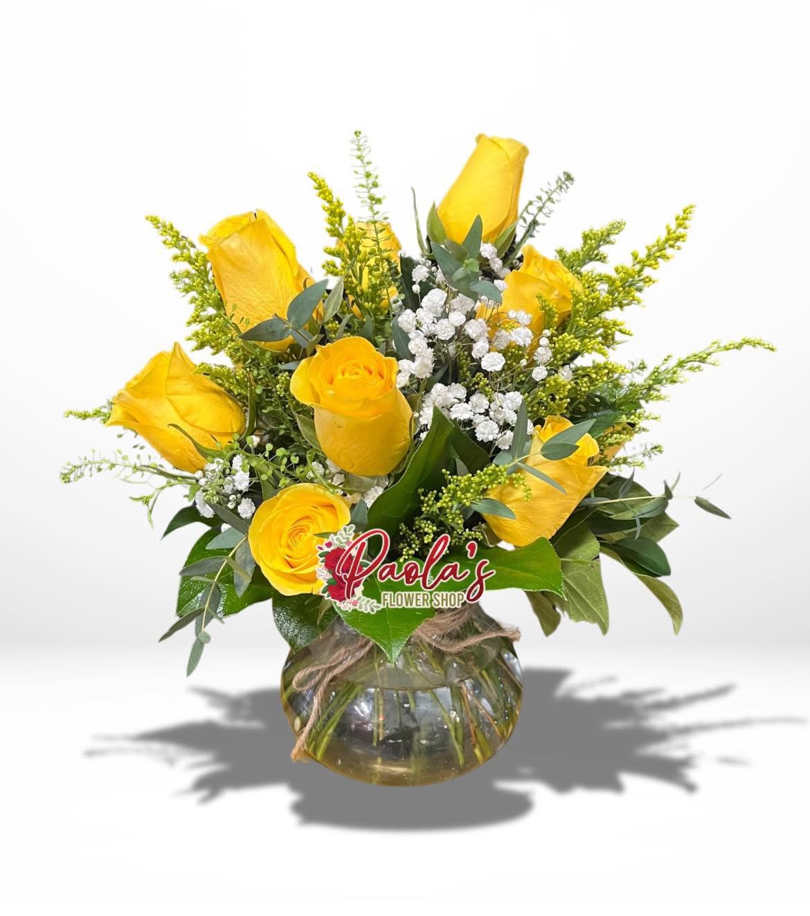Yellow roses arranged in a round glass vase with white filler flowers