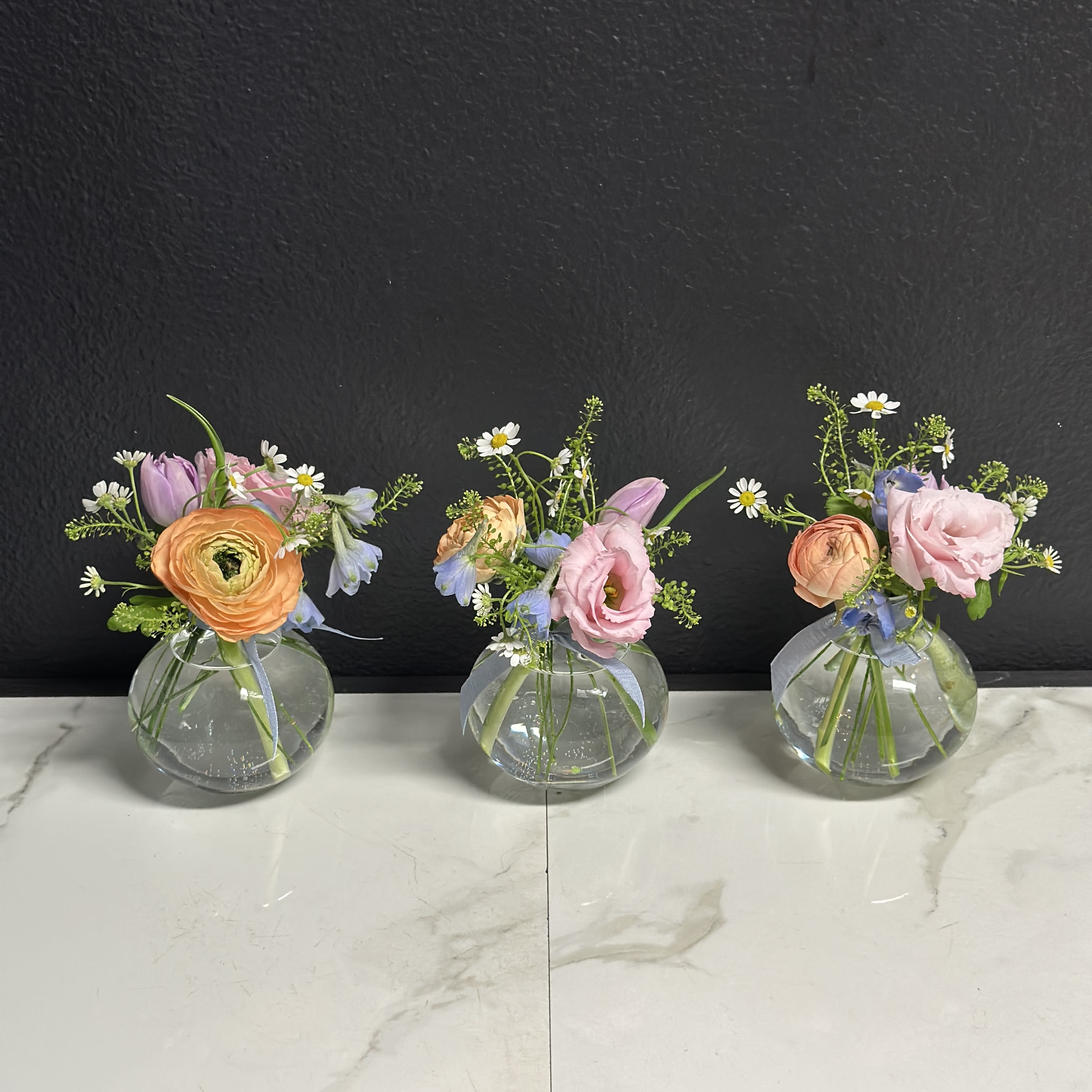 Soft Budvase Trio - A trio of budvases filled with seasonal blooms in soft pastel shades.  Budvases are typically 6-8" tall.  Floral varieties may vary but will be of similar quality &amp; style. 