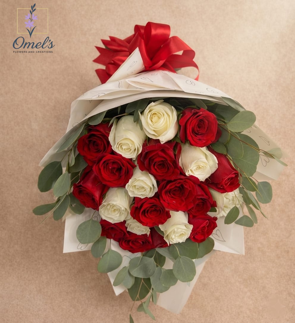 Hand-tied bouquet of red and white roses wrapped in white paper with a red bow