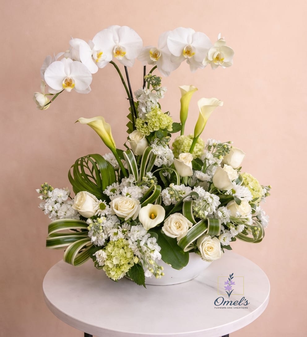 Tall white orchid and calla lily arrangement with roses in a white bowl on a round table
