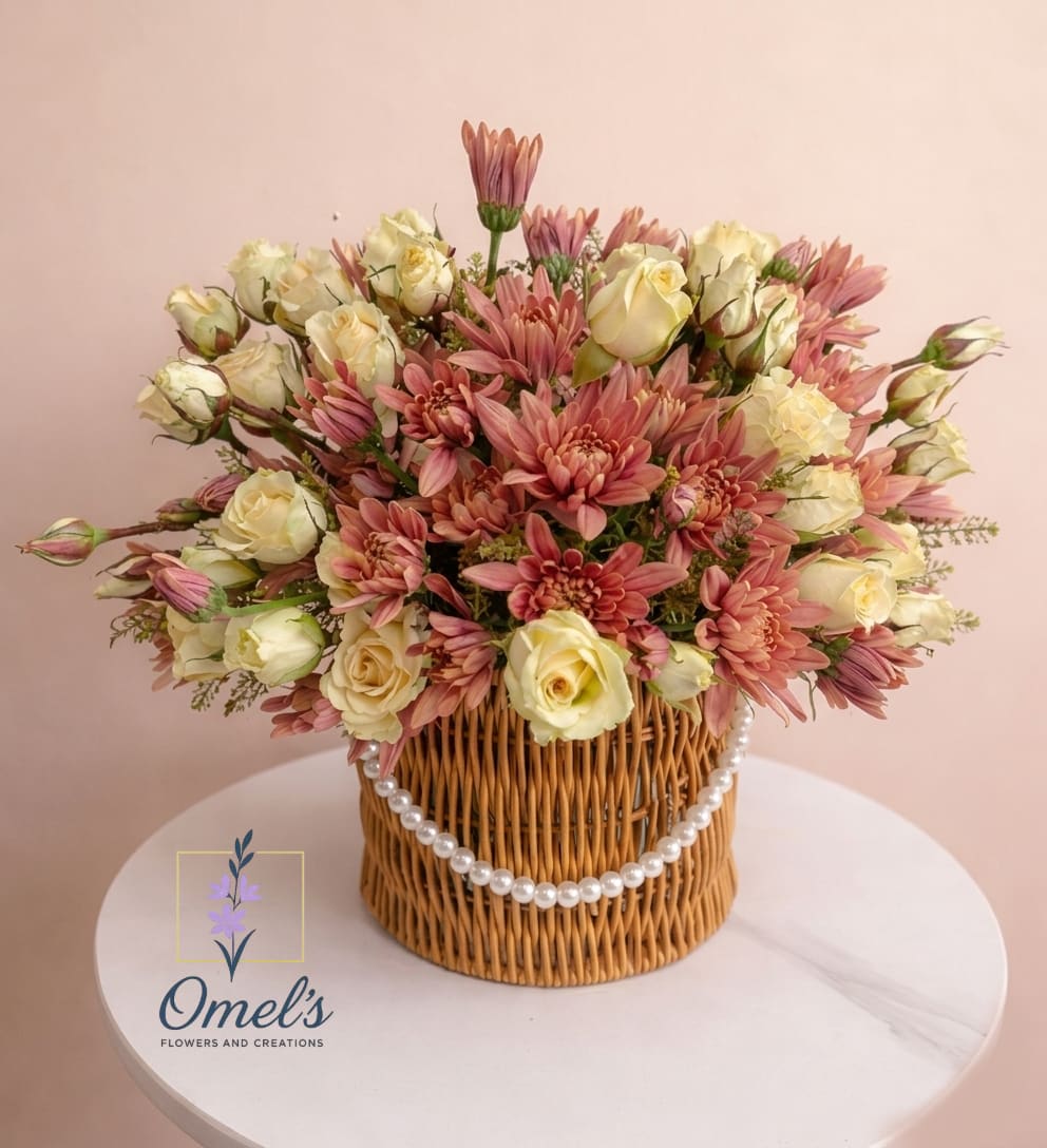 Spring Charm - A captivating blend of delicate cream and vibrant mauve, our special floral arrangement brings a unique charm to any space.  The arrangement is carefully crafted with a mix of creme roses, chrysanthemums, and various fillers to create depth and texture.  Housed in a beautifully crafted wicker vase with a string of elegant pearls, it adds a touch of natural elegance to the arrangement.  This stunning piece is the ideal gift for anniversaries, birthdays, or just to brighten someone's day, making it a truly versatile choice for any event.