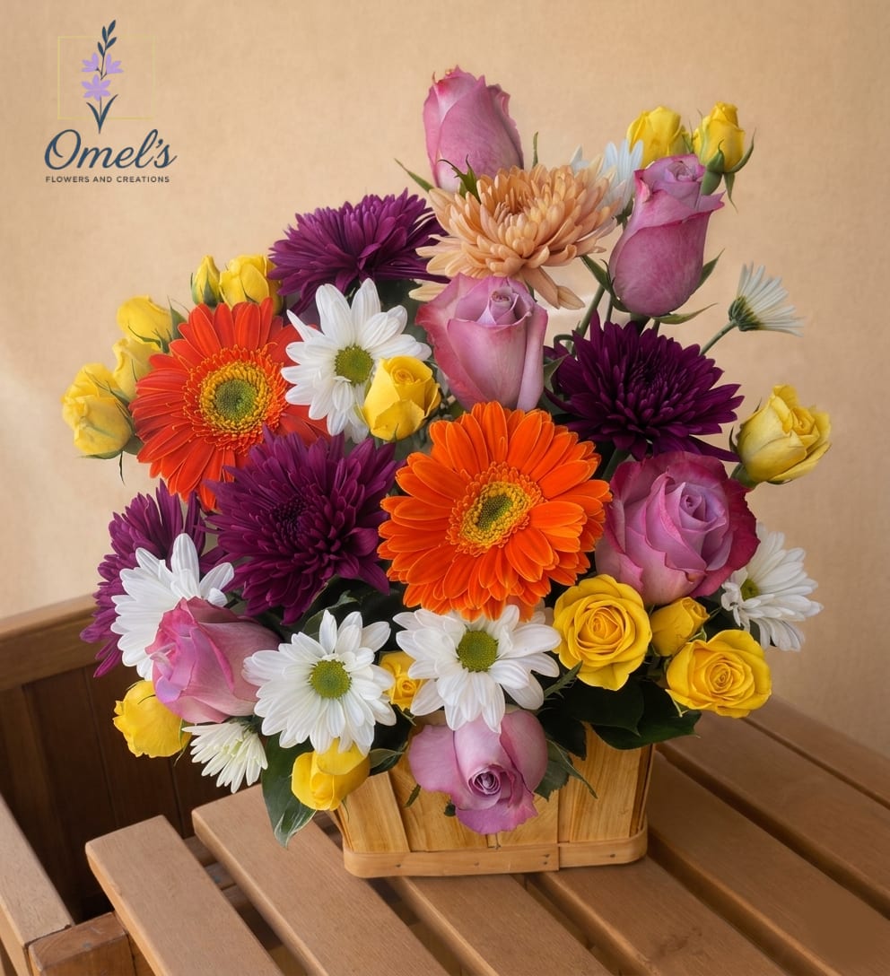 Joyful Sunset Basket - Brighten anyone's day with the "Joyful Sunset Basket," a lush and energetic arrangement bursting with color.   This stunning mix features a festive combination of bold orange Gerbera Daisies and deep purple Chrysantemums, balanced with soft lavander roses, sunny yellow spray roses, and crisp white Daisy Mums. Hand-arranged in a charming, natural split-wood basket, it brings a fresh-from-the-garden feel to any space.  This arrangement is perfect for sending congratulations, celebrating a birthday, offering encouragement and "Get Well Soon" wishes, or simply letting someone know they are in your thoughts. It makes a perfect centerpiece for a kitchen table or a delightful surprise at the office.
