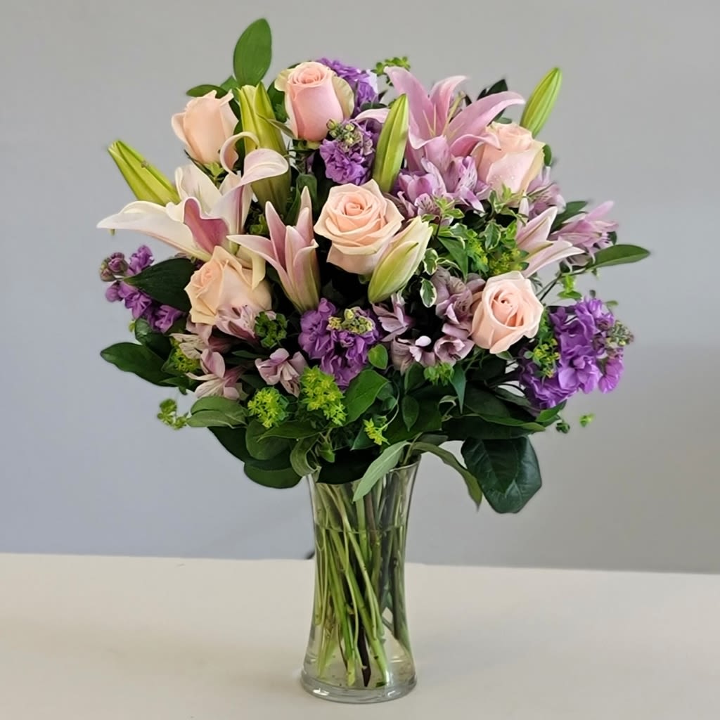 Precious Petals Bouquet - Celebrate the beauty of spring with this elegant arrangement of Lilies, Pink Roses and Purple Lisianthus.   These exquisite blooms and delicate fragrances are a perfect gift to brighten any space or make someone’s day extra special.  Approximate Size: 20" H x 12" W. Order now for a touch of seasonal charm!