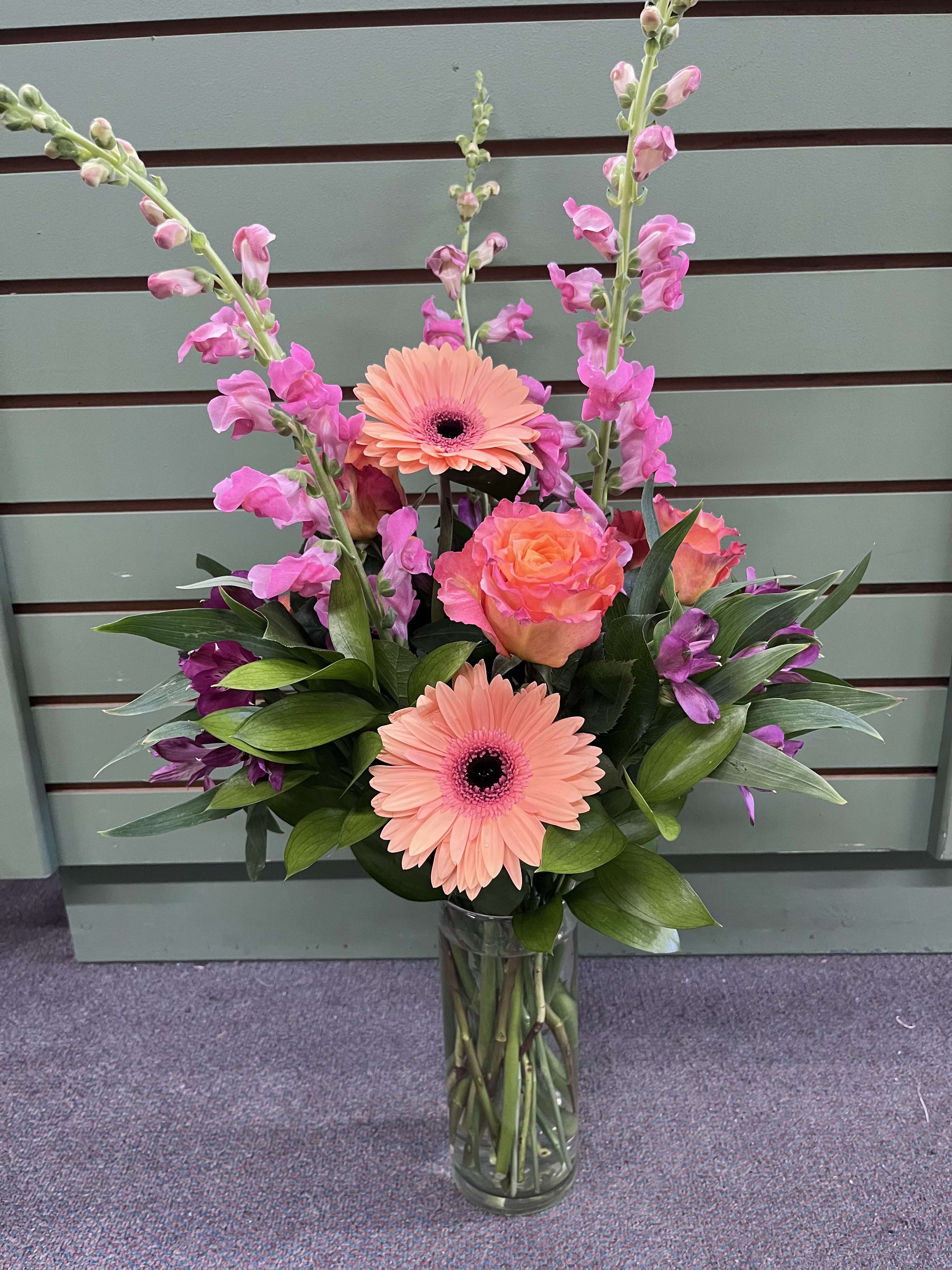 Spring Fling  - Feel the warmth and joy of spring with this beautiful arrangement!  Spring Elegance is sure to brighten anyone's day with its bright beautiful colors! It's the perfect arrangement for any occasion including but not limited to, get well, thinking of you, love and romance, and just because.   This arrangement features pink snapdragons, peach gerbera daisies, free spirit roses, and purple alstroemeria. 