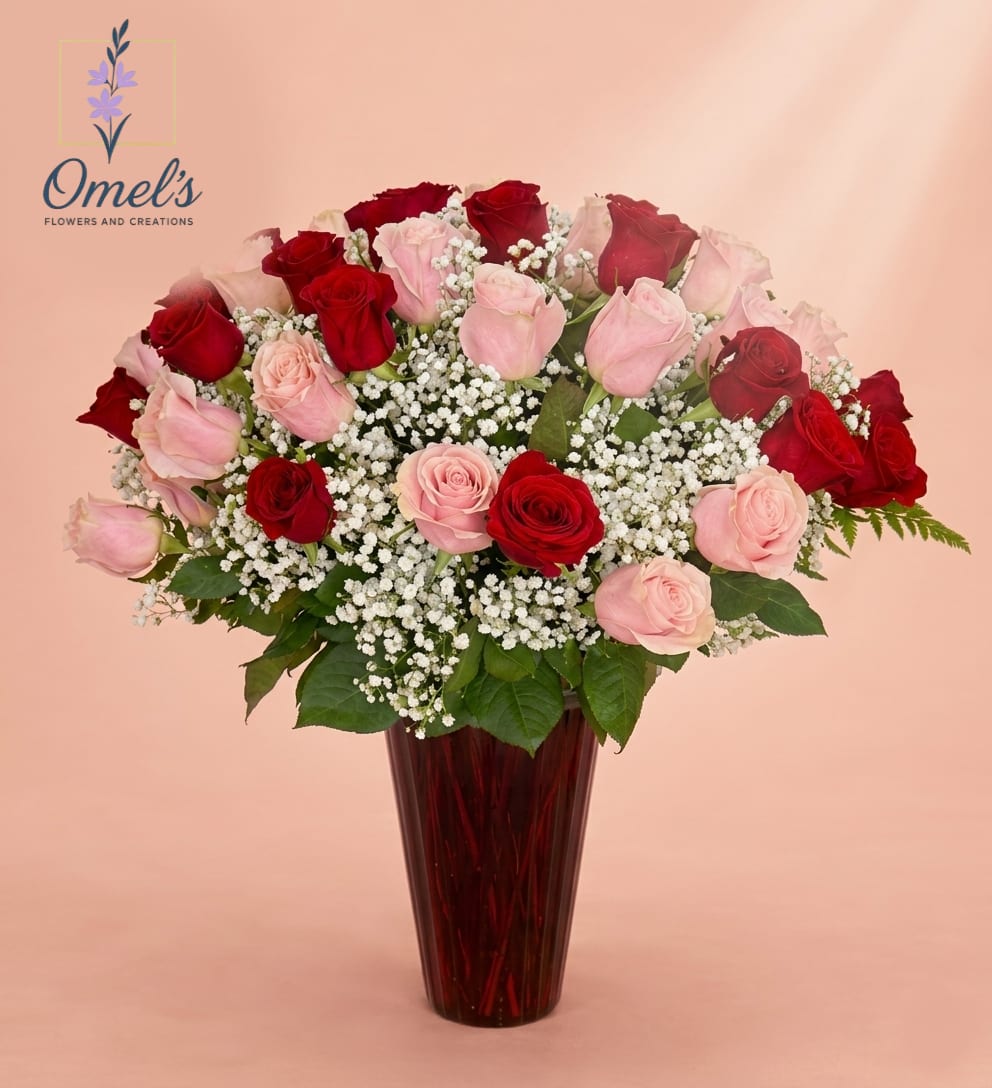 Radiant Love Bouquet - Express your deepest affections with "Radiant Love Bouquet," a masterpiece of floral design that balances elegance and vibrancy. This grand arrangement is meticulously crafted in a high-fidelity style, presenting a harmonious blend of velvety deep red roses and soft, delicate light pink roses. The rich colors of the roses are beautifully contrasted by a profusion of white baby's breath, creating a luxurious and full texture.  Nestled within a tall, elegantly fluted, translucent ruby-red glass vase that catches and scatters the light, this arrangement exudes sophisticated charm. The lush green foliage provides a natural, grounded base, ensuring every bloom is presented at its best.  This stunning bouquet is the ideal choice for occasions that demand a grand gesture, including Valentine's Day; romantic anniversaries; special birthday celebrations for a loved one; proposals and engagements; Mother's Day, to honor a mother's graceful and vibrant spirit.