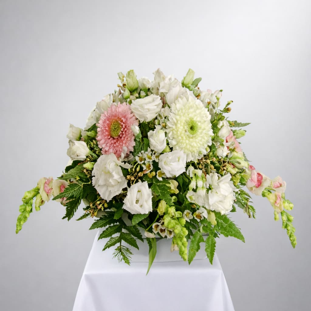 Cherished Blush Bouquet - A tender expression of warmth and remembrance. This design features a graceful blend of snapdragons, lisianthus, gerberas, poms, carnations, and airy wax flowers in soft whites and blush‑pink tones. The palette is intentionally gentle, creating a soothing, uplifting presence for any meaningful moment.  Each arrangement is handcrafted with care, inspired by the style and feeling you envision. Because every creation is made uniquely for you, natural variations in blooms may occur. Seasonal availability can influence flower selection and pricing, but the overall look and sentiment will always remain true to the design’s spirit.  A serene, heartfelt composition for honoring, celebrating, or simply sending comfort.