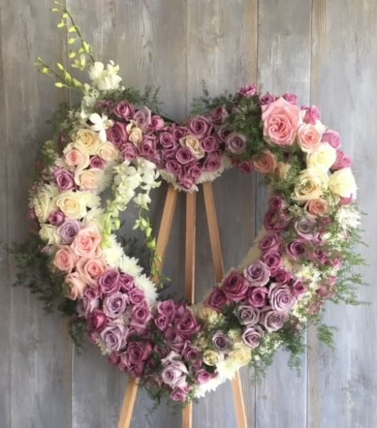 Forever Love Heart Wreath II - This beautiful open heart wreath is a stunning tribute to a loved one. Featuring a combination of pink, lavender, and white roses, as well as delicate dendrobium orchids, this arrangement is a sweet and elegant expression of your love and sympathy. Measuring approximately 24 inches in size, it is sure to make a meaningful and lasting impression.