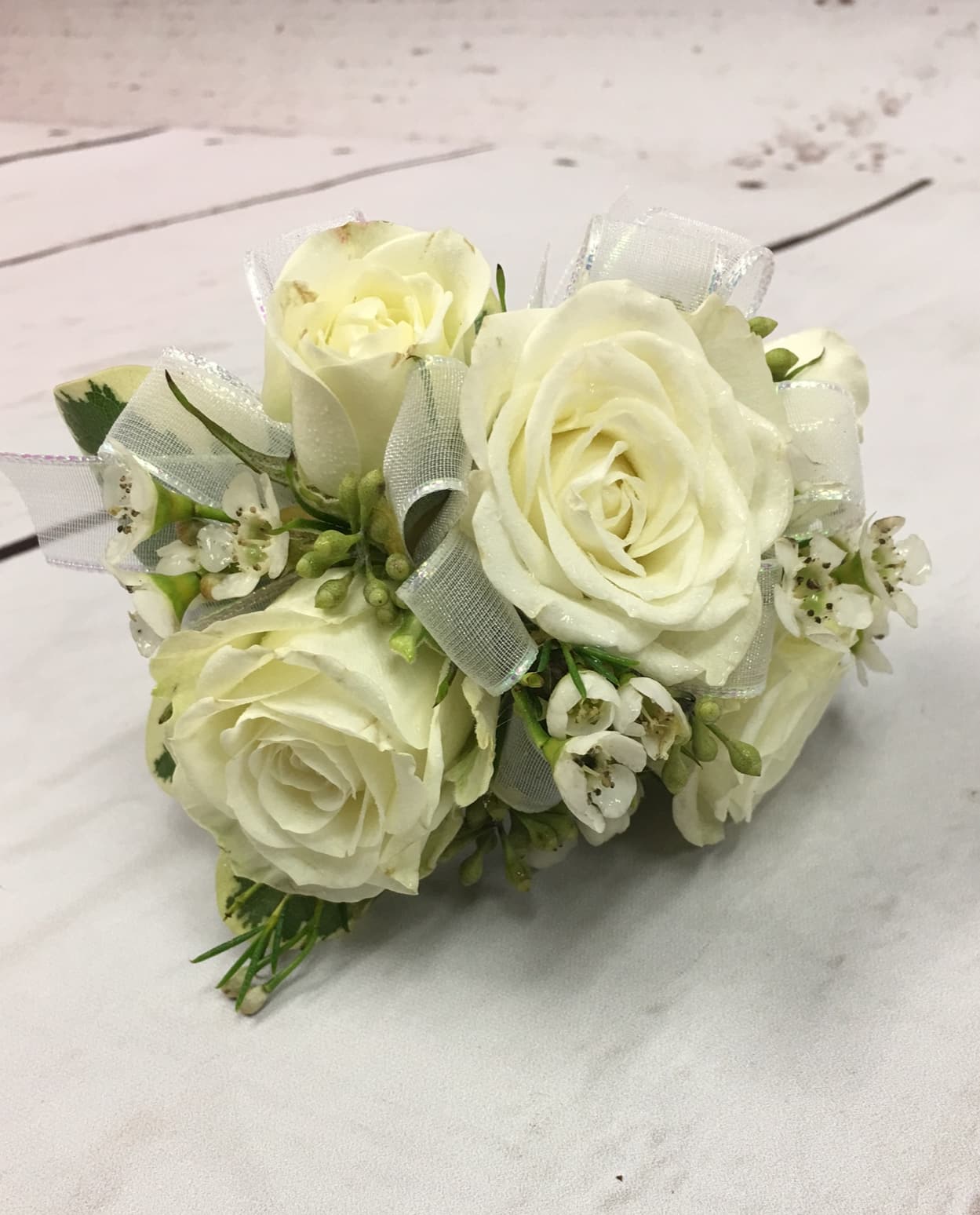 Simple White Spray Rose Velcro Wrist Corsage  - White spray roses, white sheer ribbon accented with white, or soft pink, filler flower on a velcro wristlet.  We can change ribbon to match or compliment any dress color. Please note ribbon color on order and/or rose color.  Spray rose colors: light pink, hot pink, lavender, yellow, red, and orange.   