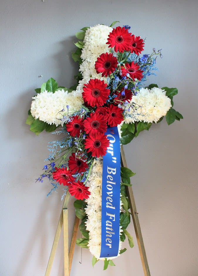 Funeral standing cross 24" -  You Cross My Heart #57 - Easel stand included. This 24" cross includes white daisies, red Gerber daisy and blue filler and greens. Colors can be changed at clients request 