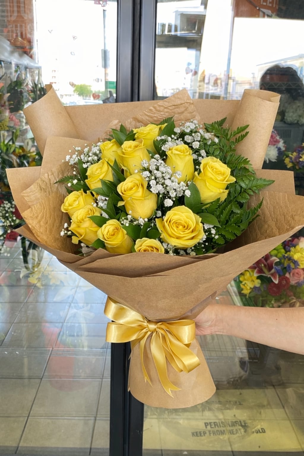 Golden Elegance 12 Rose Bouquet  - An elevated bouquet of 12 fresh yellow roses arranged with filler flowers and greenery wrapped in Kraft paper. 
