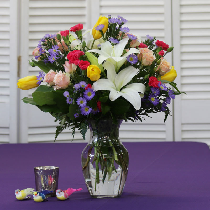 Dazzling Delicate Collection - This Dazzling arrangement comes with White Lilies, Yellow Tulips, Hot Pink Mini Carnations, Pink Spray Roses, and Purple Novi Belgi.