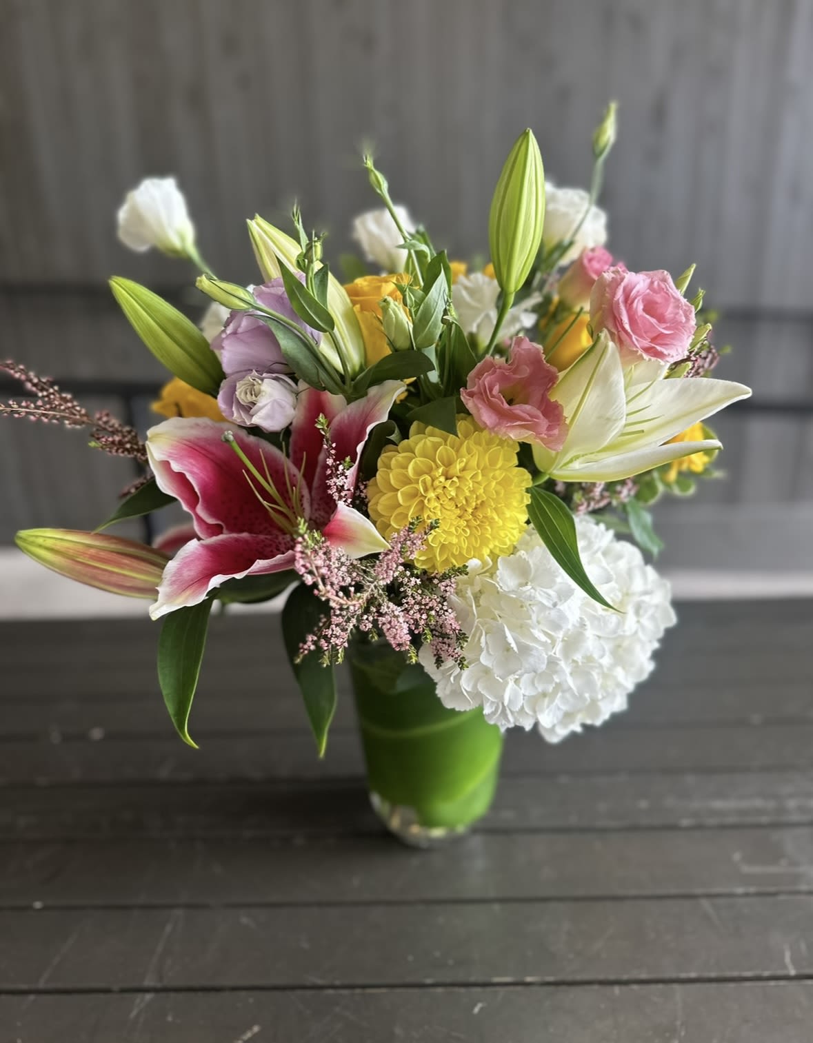 Sunny  - A medium height cylinder vase filled with hydrangeas, lilies, roses, dahlias, lisianthus and seasonal fillers. 