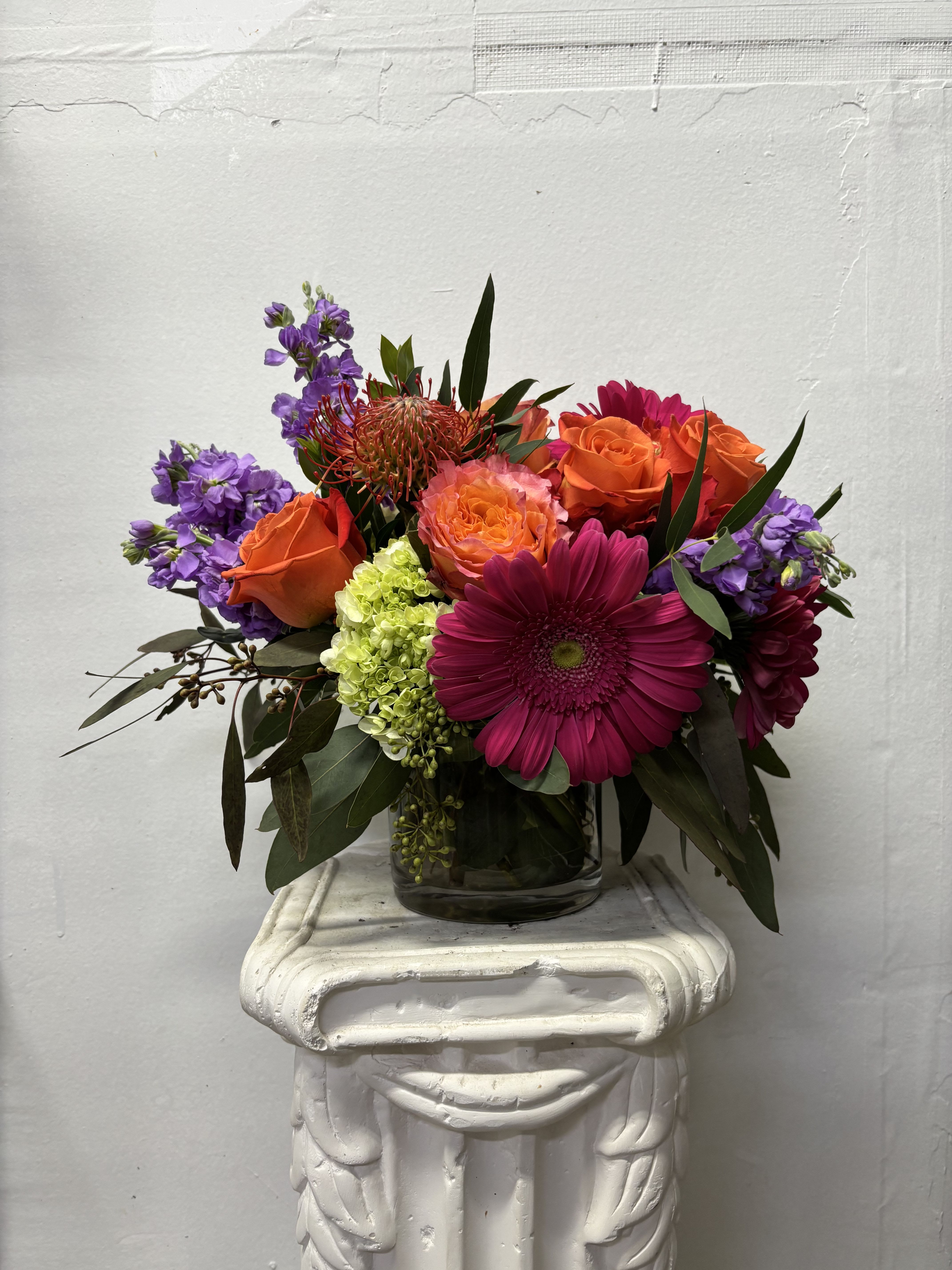 Free Spirit - Orange roses and hot pink Gerber Daisies with purple stock, green hydrangeas, and other orange blooms