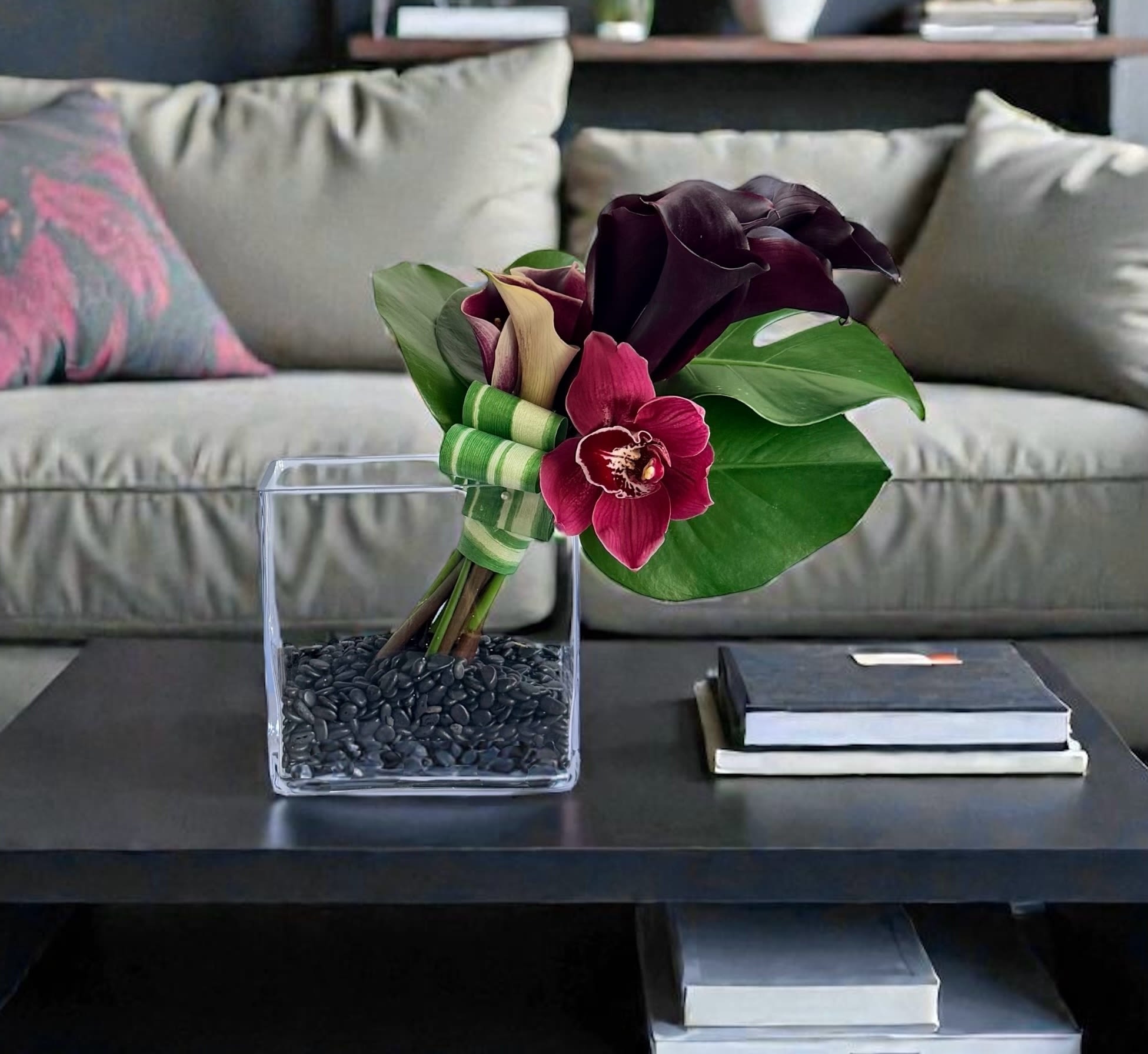 Dark purple calla lilies and orchid in a square glass vase