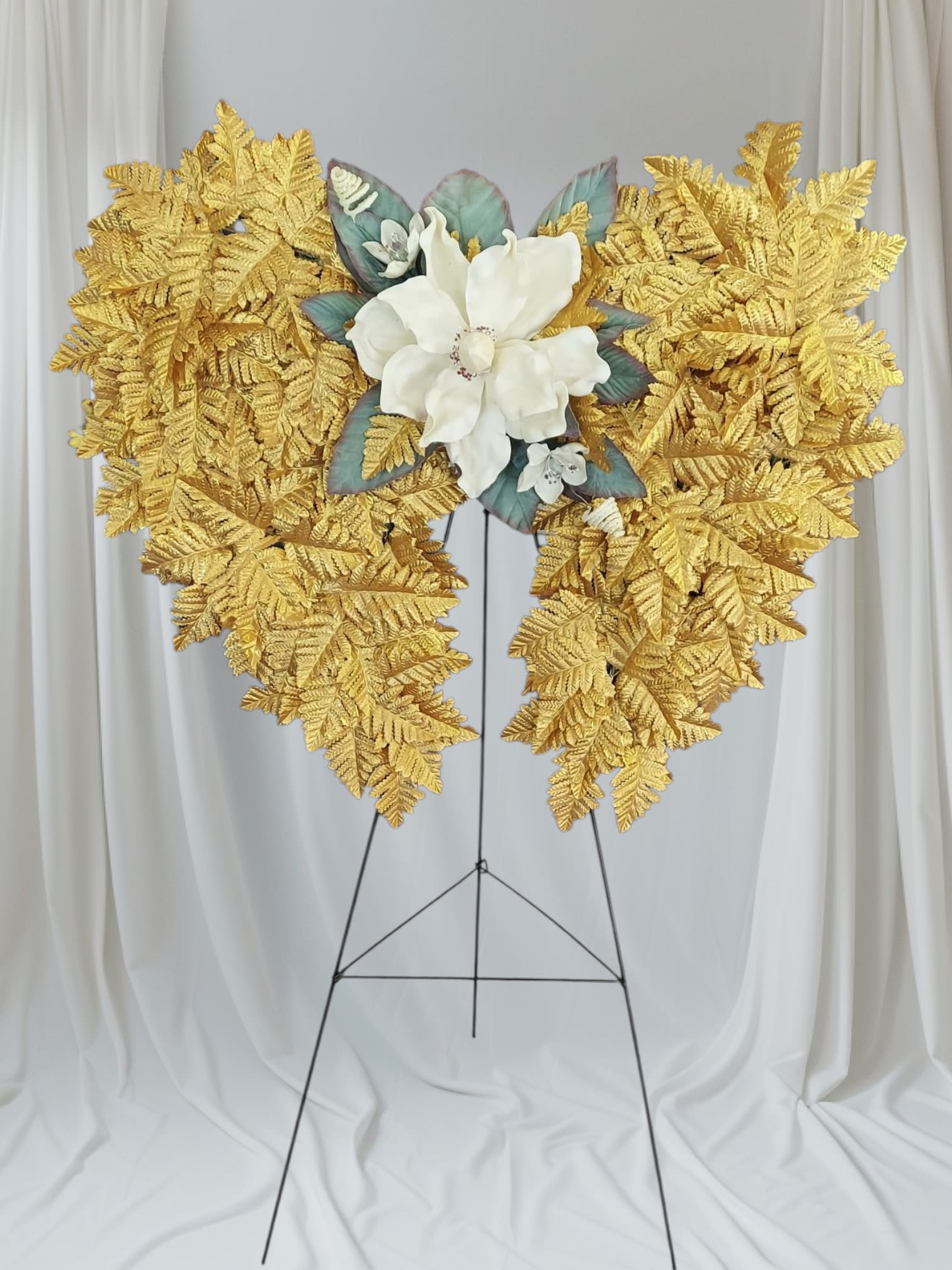 Golden Wings Standing Spray -  Faux golden leaves in the shape of angel wings adorned with a faux white magnolia bloom. Wreath is attached to a 48" easel.