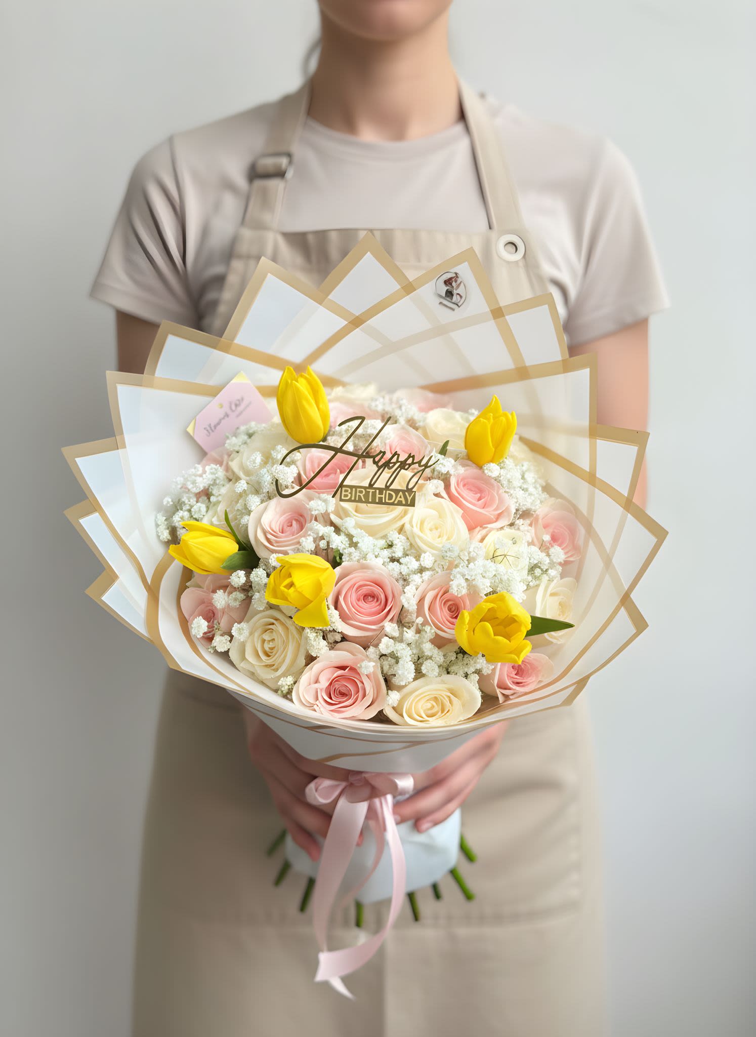 Pink &amp; White Birthday Bouquet - Celebrate their special day with our Blush Birthday Garden Bouquet   This elegant arrangement features a beautiful mix of soft pink and ivory roses, delicate baby’s breath, and vibrant yellow tulips, wrapped in premium layered paper for a modern and luxurious presentation. Finished with a “Happy Birthday” topper, this bouquet is designed to brighten any celebration.  Perfect for birthdays, surprises, or thoughtful gifts, this bouquet brings a soft, cheerful, and elegant touch to any moment.  Each bouquet is handcrafted with care to ensure fullness and balance.  Please note: Flower shades and bloom stages may vary. Tulips may arrive slightly closed for longer-lasting freshness.