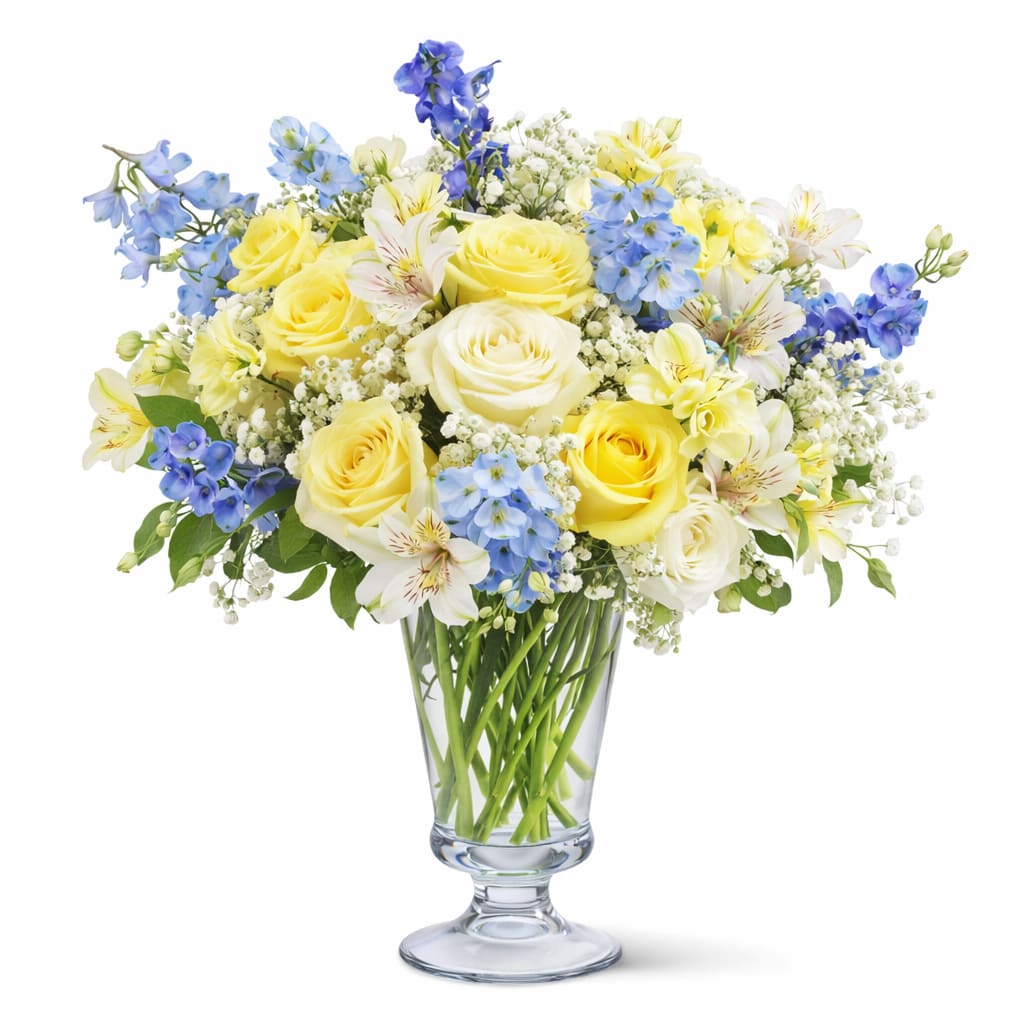 Buttercup &amp; Blue - Yellow and white roses, alstroemeria, blue delphinium, baby’s breath, and seasonal greenery arranged in a tall clear glass vase.  *Vase/container may vary depending on availability of stock at time of purchase. *We strive to use the flowers shown whenever possible; however, substitutions of equal or greater value may be made based on seasonal and market availability. 