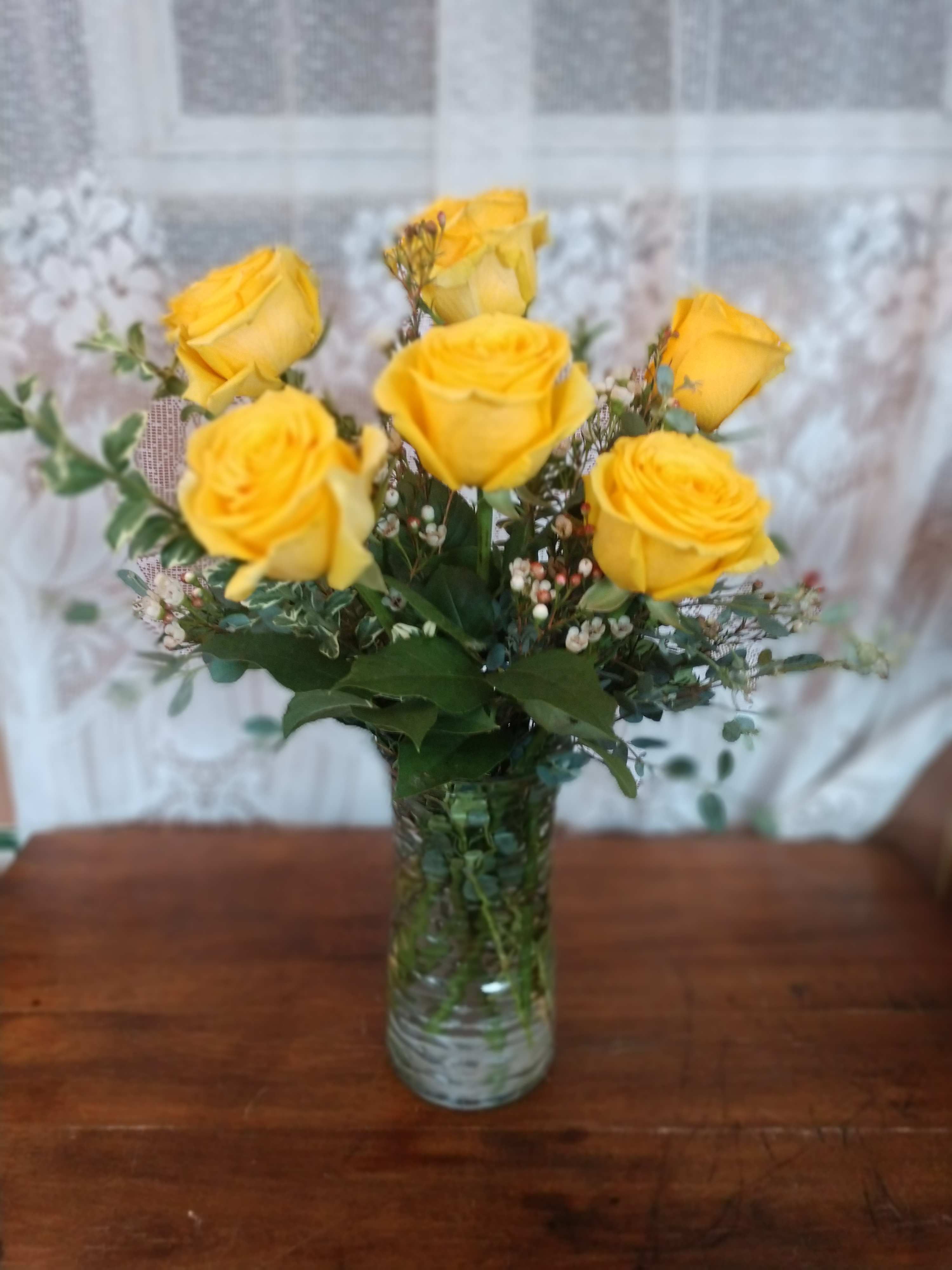 Sunshine - Sunshine yellow roses are sure to brighten any ones day. These sunny yellow roses are accented with wax flower and assorted greenery all in a glass vase.