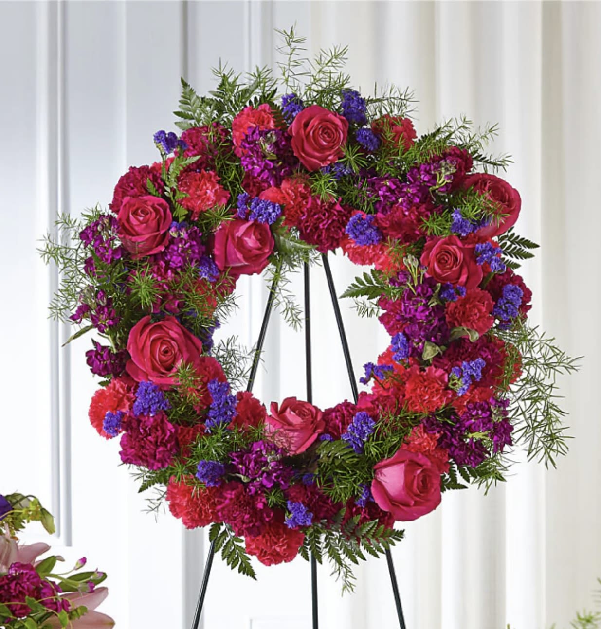Forever Radiant Wreath - Forever Radiant Wreath | Wilmington, Delaware Florist  Celebrate a vibrant life with our Forever Radiant Wreath, a bold and beautiful sympathy tribute handcrafted by Petals Flowers and Fine Gifts in Wilmington, Delaware. This standing funeral wreath features a striking mix of hot pink roses, rich purple statice, magenta stock, and other vivid pink blooms, artfully arranged in a lush, circular design that symbolizes eternal love and remembrance.  Whether displayed at a funeral service, memorial, or graveside ceremony, Forever Radiant Wreath offers a heartfelt way to honor a loved one’s bright spirit and lasting legacy. Its radiant colors bring comfort and beauty during life’s most difficult moments.  As your trusted local florist in Wilmington, Delaware, we provide same-day, tax-free delivery to Wilmington, Hockessin, Newark, Chadds Ford, Glen Mills, Kennett Square, and surrounding areas.  Why Choose Us? * Custom-designed funeral and sympathy wreaths with a satisfaction guarantee * Locally owned and operated flower shop in North Wilmington * Compassionate, personalized service with premium fresh flowers  Send a powerful message of love and remembrance with our Forever Radiant Wreath—a vibrant tribute professionally crafted and delivered by your local Wilmington florist.