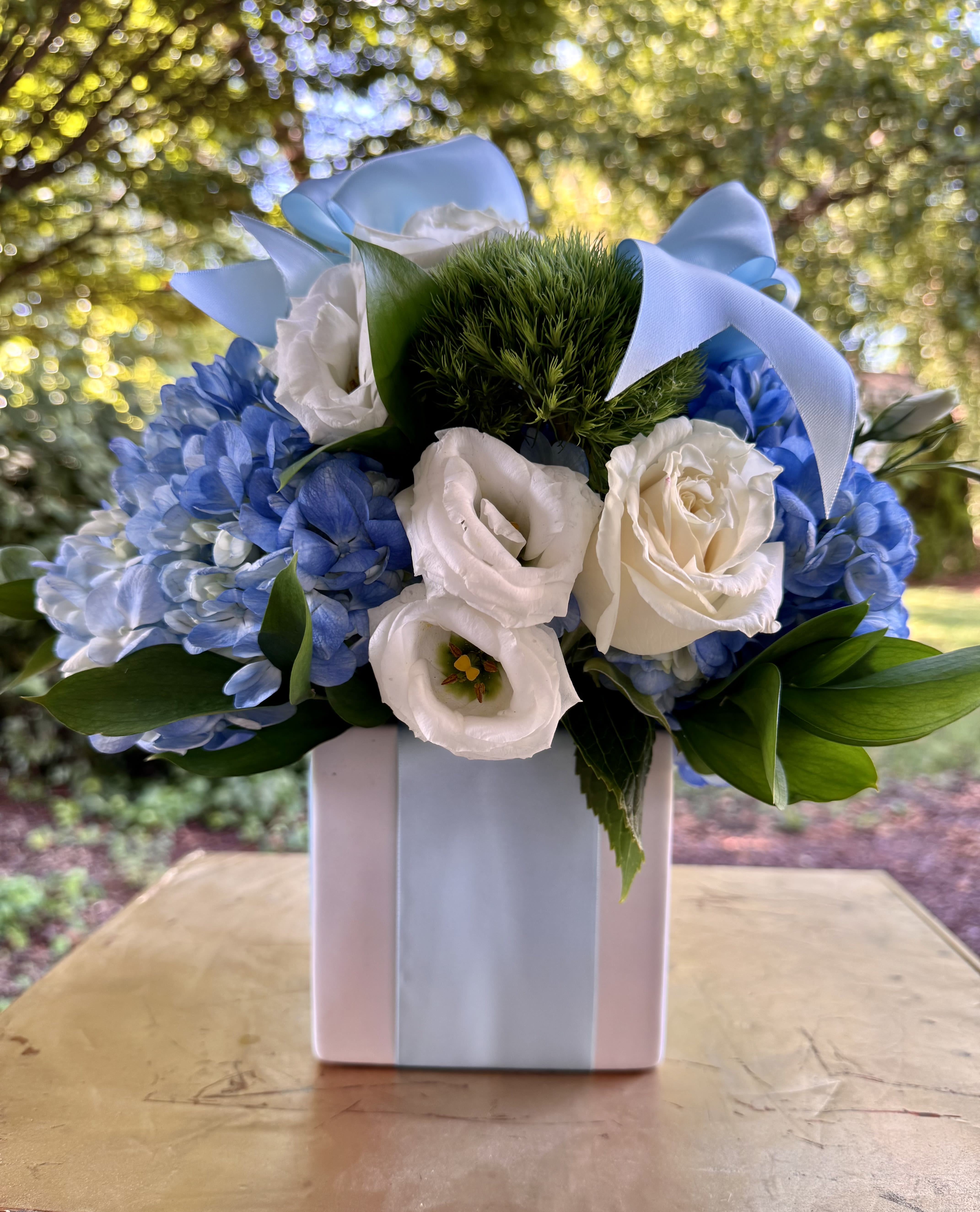 A Gift For Him - A Gift for Him | Wilmington, Delaware Florist  Looking for the perfect way to celebrate a special man in your life? Our A Gift for Him arrangement, exclusively designed by Petals Flowers and Fine Gifts — your trusted local florist in Wilmington, Delaware — offers a sophisticated mix of color and texture that’s both fresh and refined.  This stylish design features striking blue hydrangea, elegant white roses, and textured green trichelium, thoughtfully arranged in a modern white cube container and finished with a light blue satin ribbon for an added touch of charm. The cool color palette and clean presentation make it ideal for birthdays, promotions, Father’s Day, or simply to show your appreciation.  As a boutique florist in Wilmington, Delaware, we take pride in crafting custom, high-quality floral arrangements with premium blooms and artistic detail. We offer same-day, tax-free flower delivery throughout Wilmington, Hockessin, Newark, Glen Mills, Chadds Ford, Kennett Square, and nearby areas — always backed by our satisfaction guarantee.  Why Choose Us?  * Locally owned Wilmington florist known for creativity, quality, and personal service * Deluxe, hand-crafted arrangements tailored for any occasion * Reliable same-day delivery across Wilmington and surrounding communities Order A Gift for Him today and let Petals Flowers and Fine Gifts deliver a thoughtful, elegant expression right to your loved one’s doorstep in Wilmington, Delaware.