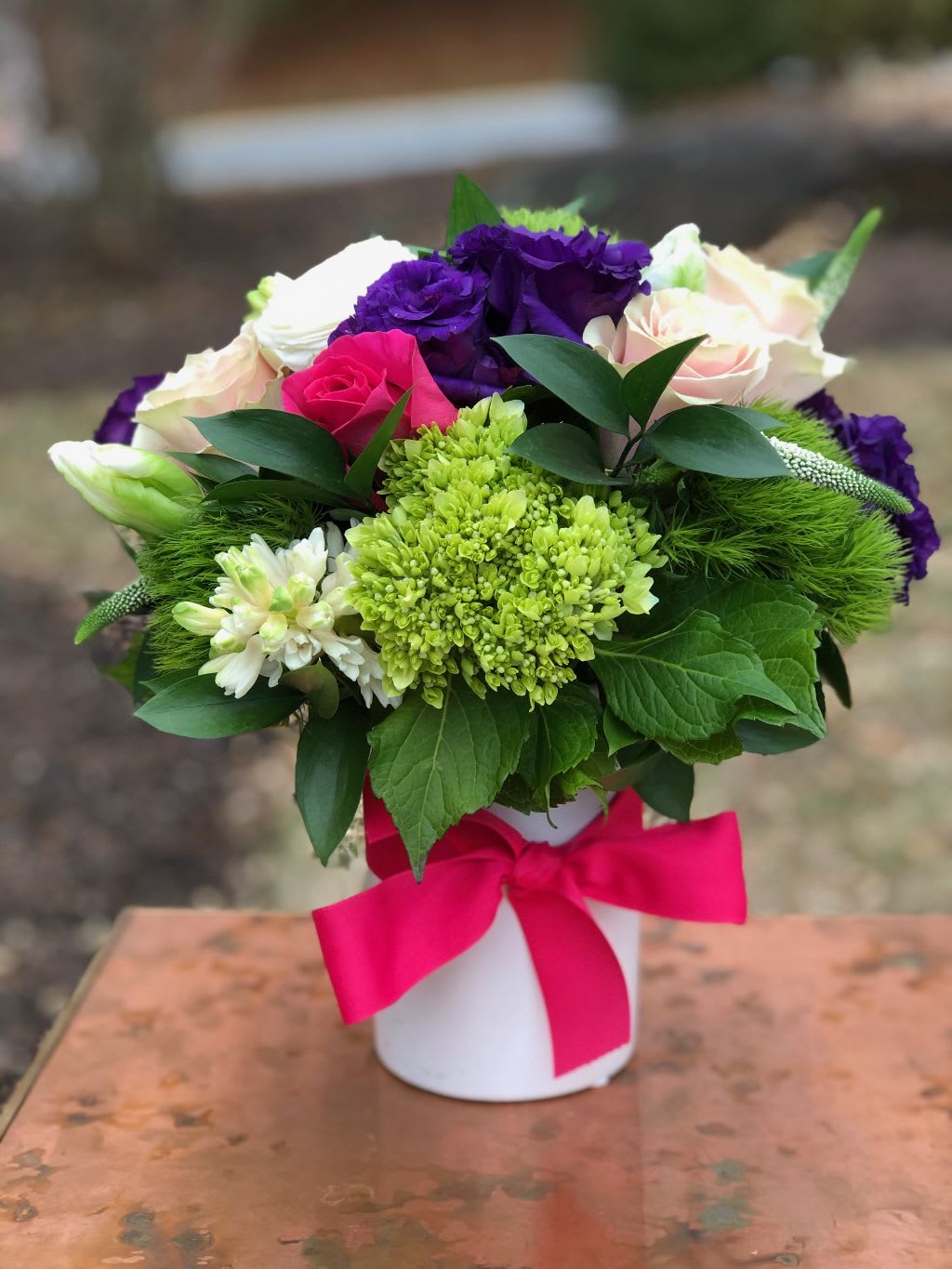 Promise of Spring - The Promise of Spring – Fresh Pink, Purple, and Green Floral Arrangement | Wilmington, DE Local Florist  Celebrate the beauty of the season with The Promise of Spring, a vibrant floral design handcrafted by Petals Flowers and Fine Gifts, your trusted Wilmington, Delaware florist. This cheerful arrangement features lush green hydrangea, delicate pale pink roses, bold dark pink roses, and striking dark purple lisianthus. Presented in an elegant white cylinder vase and finished with a bright hot pink ribbon, this arrangement brings a fresh burst of color perfect for birthdays, anniversaries, or just because.  We proudly provide same-day flower delivery in Wilmington, DE, as well as to nearby areas including Hockessin, Newark, Glen Mills, Chadds Ford, Christiana, and Kennett Square.  Why Choose Us:  * Locally owned and operated boutique florist with deep ties to the Wilmington, Delaware community * Hand-crafted, premium floral arrangements designed with care and creativity * Dedicated to exceptional customer service with a 100% satisfaction guarantee * Enjoy tax-free flower delivery on all orders Order The Promise of Spring today from Petals Flowers and Fine Gifts and brighten someone’s day with a fresh, colorful gift that’s sure to impress.