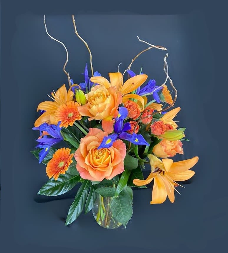 Brilliant Bouquet - This brilliant bouquet will help you welcome in the warm weather of spring with its bursting display of orange lilies, orange roses, purple iris, and orange gerbera daisies.